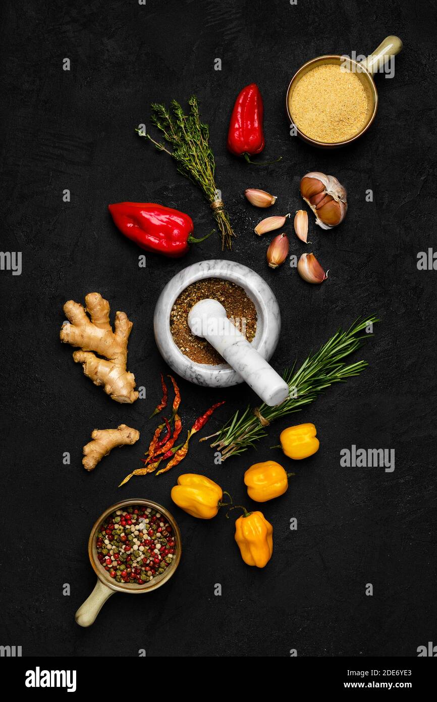 Composition with mixture of peppers, ginger, garlic, thyme, chilli and rosemary on dark background Stock Photo