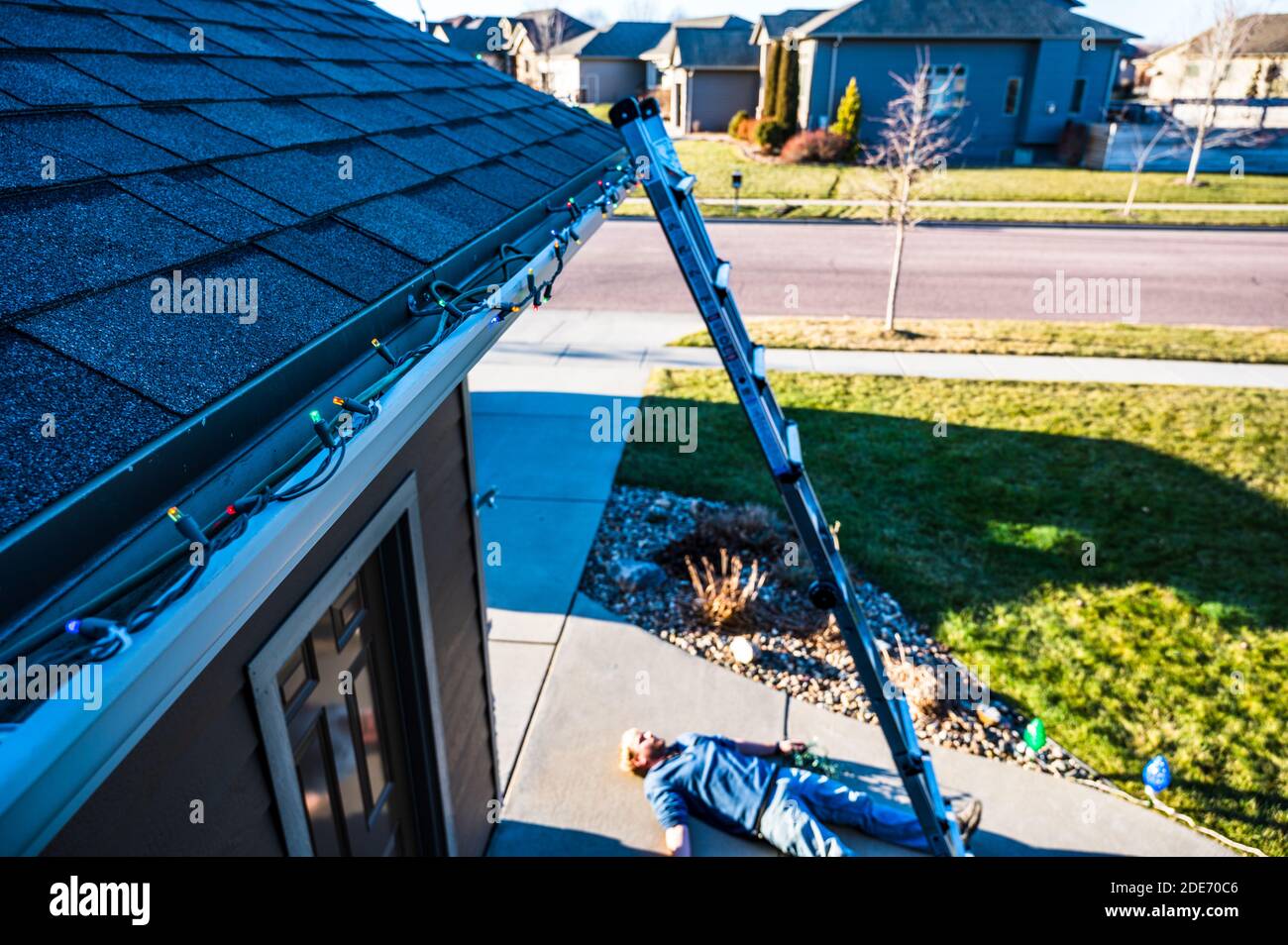 Concept of falling danger involved with hanging Christmas lights on the roof and falling from heights Stock Photo