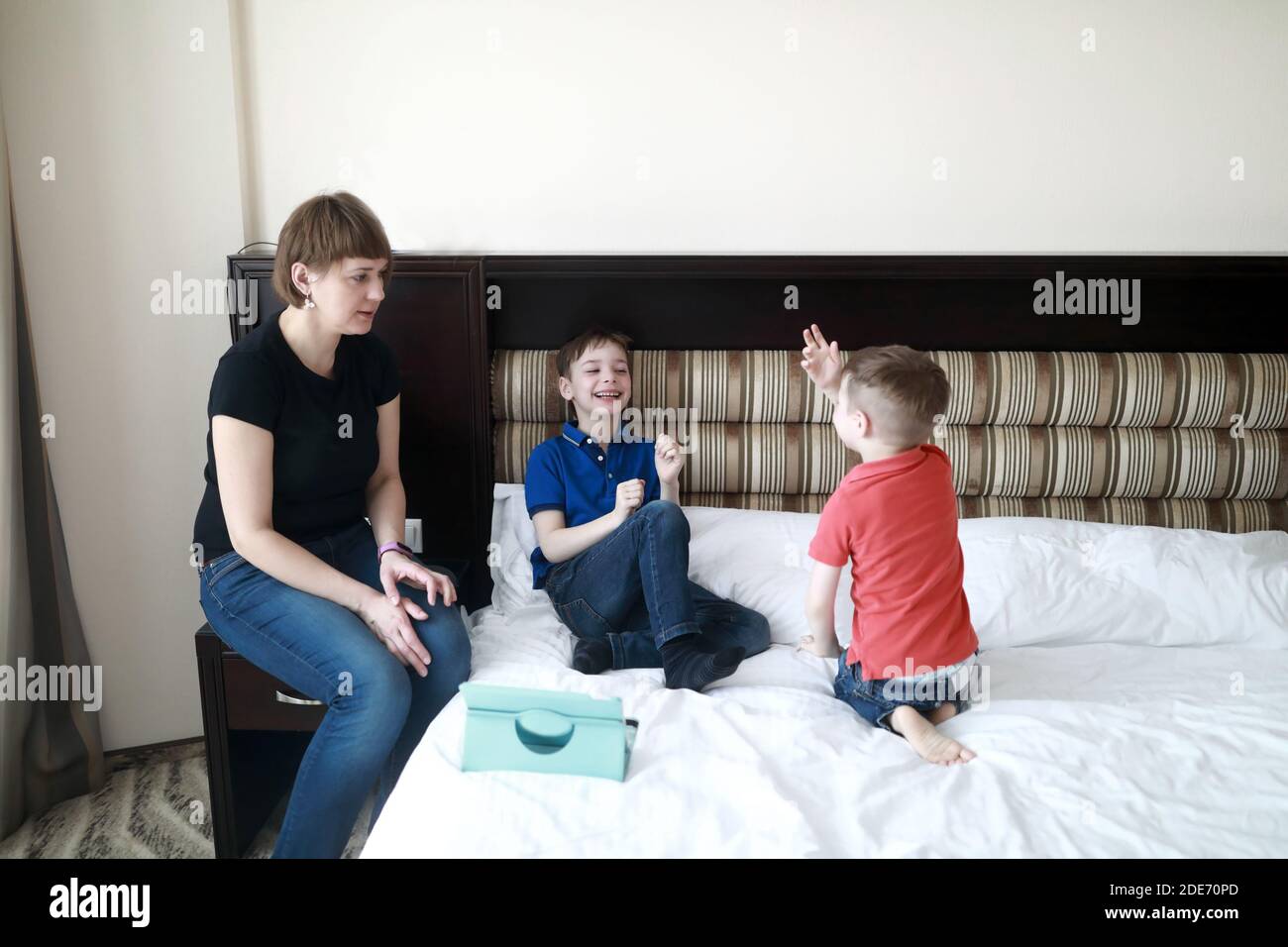 Mother with sons on bed in hotel room in the morning Stock Photo - Alamy
