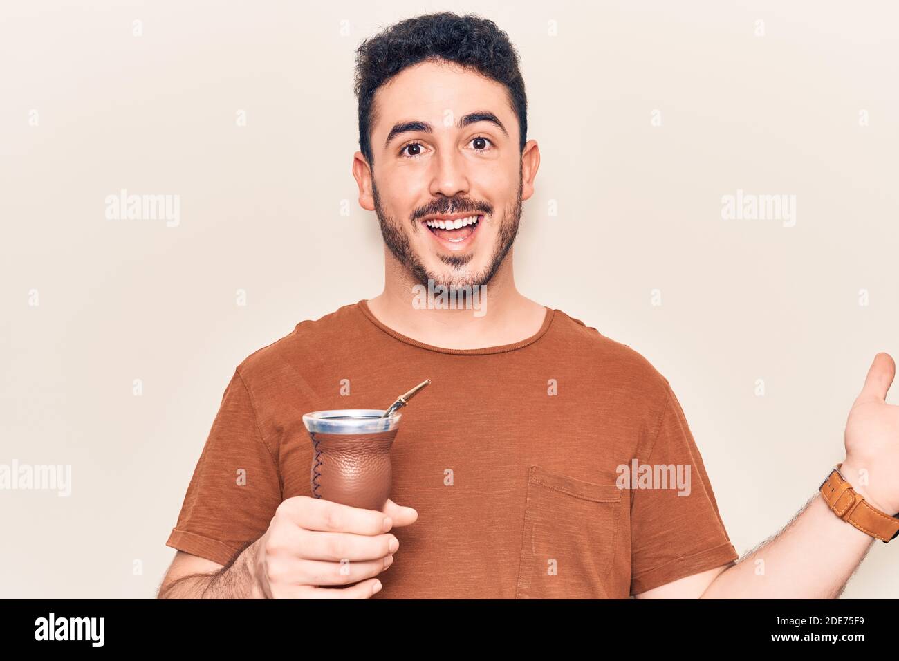 Young hispanic man drinking mate infusion celebrating achievement with ...