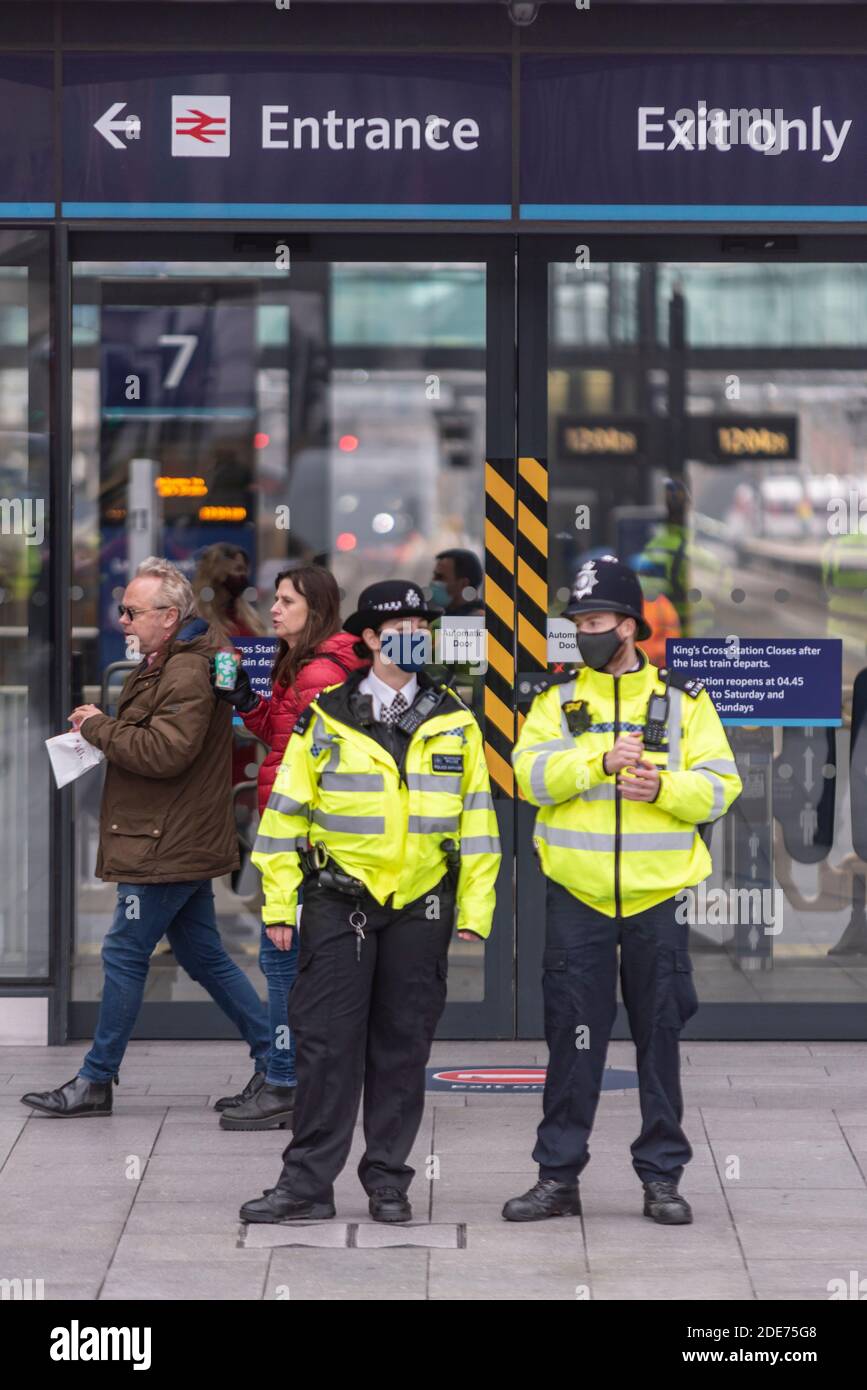 Police officers outside Kings Cross railway station in preparation for a COVID 19 Coronavirus anti lockdown protest march in London, UK. Entrance door Stock Photo