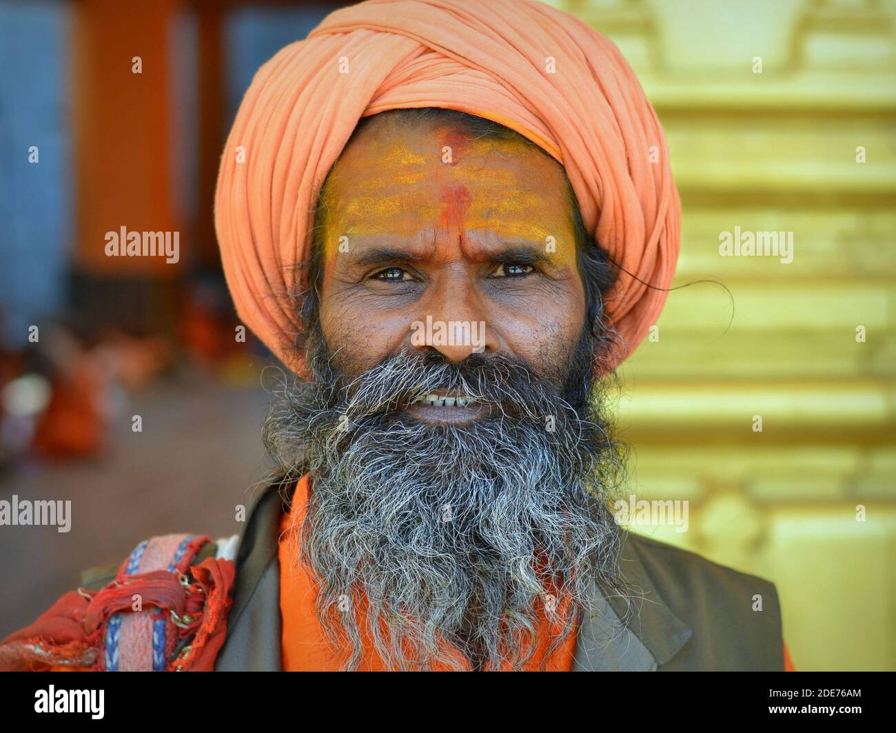 Elderly Indian Hindu holy man (sadhu, baba, guru) with a yellow tripundra painted on his forehead poses for the camera during Shivratri Mela festival. Stock Photo