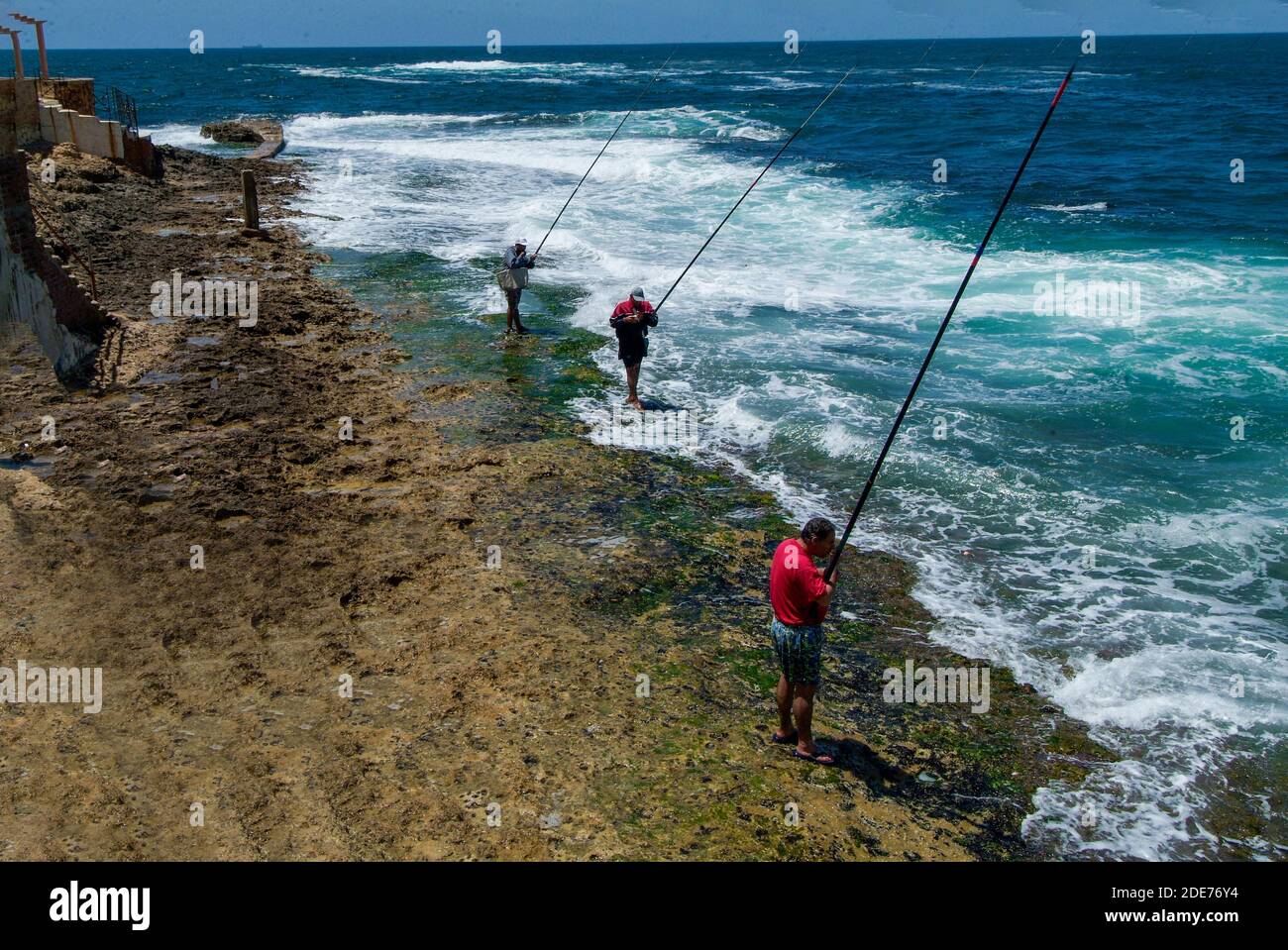 05-31-2007 Alexandria , Egypt . Fishermen (3  person )on coast of Mediterranean Sea with big fishing rods Stock Photo
