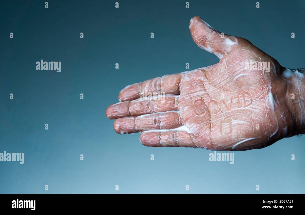 Coronavirus becomes ineffective with soap. the man's soapy hand written 'covid-19' Stock Photo