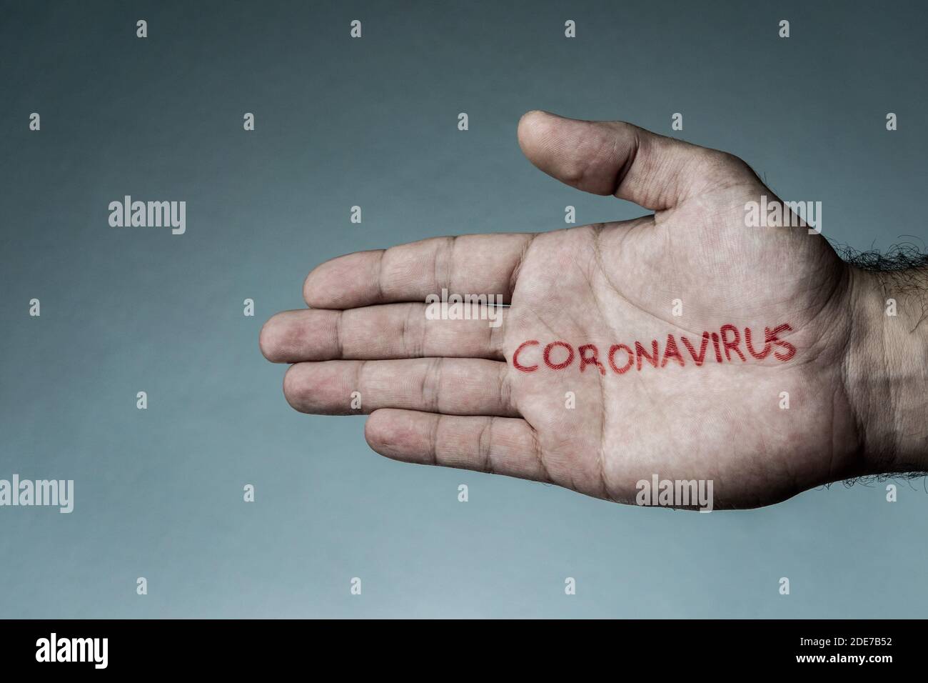 Coronavirus text written on hand of man. Covid-19, Coronavirus, SARS-CoV-2 outbreak. 2019 Novel Coronavirus concept and blue background. Stock Photo