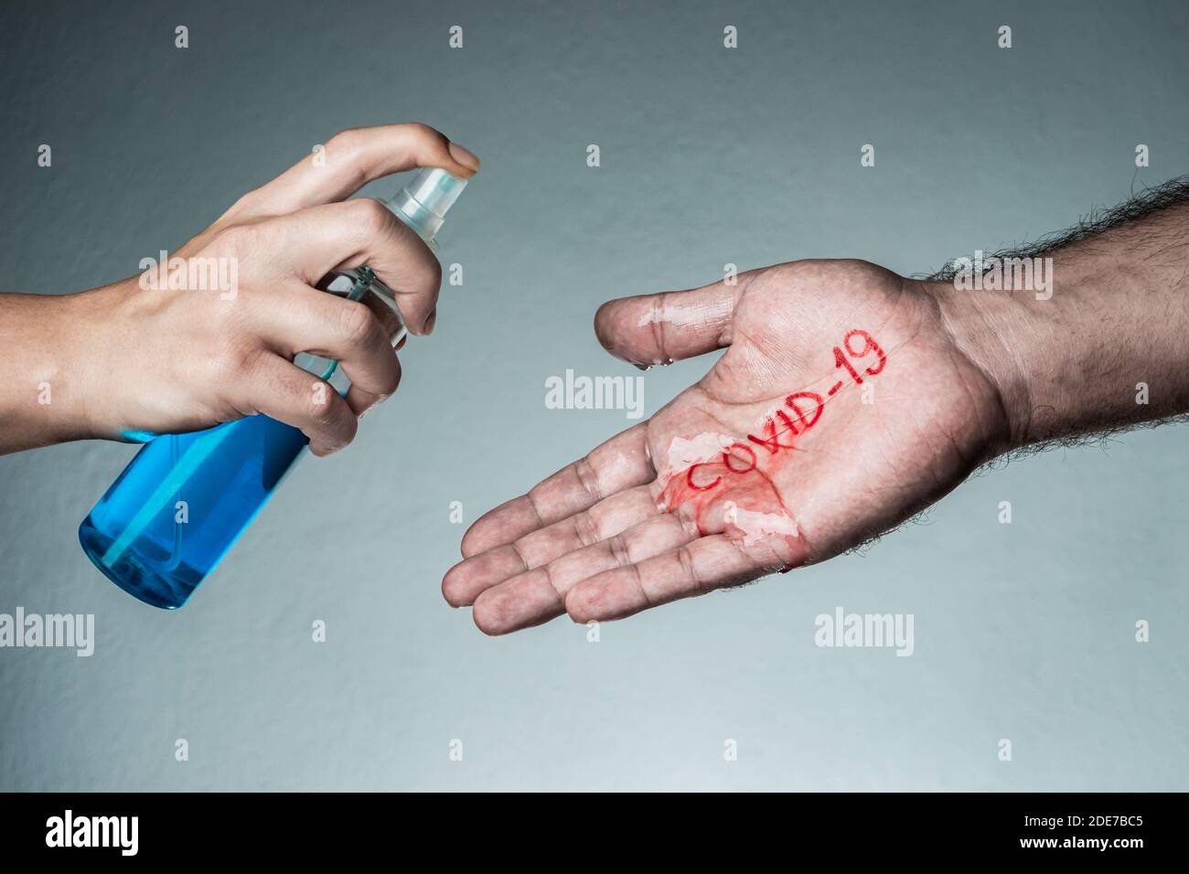 Woman spraying disinfectant into man's hand. Covid-19, Coronavirus, SARS-CoV-2 outbreak. 2019 - 2020 Novel Coronavirus concept and background. Stock Photo