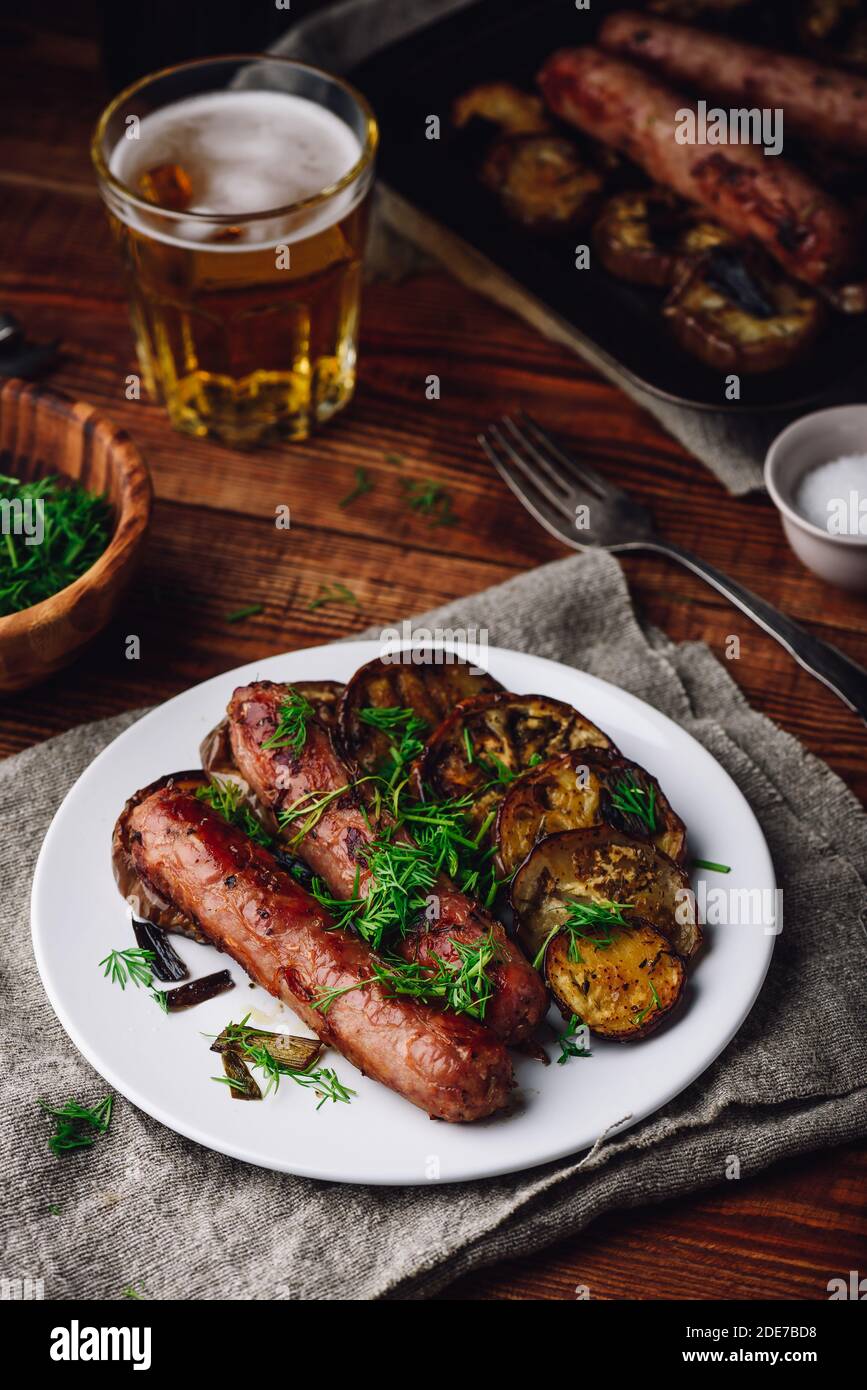 Pork Sausages Baked with Eggplant Slices on White Plate Garnished with
