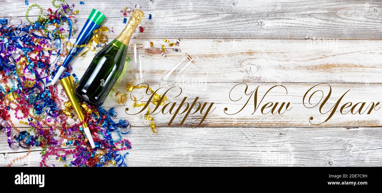 New Year eve party decorations and champagne with drinking glasses on rustic white wooden background plus written text message Stock Photo