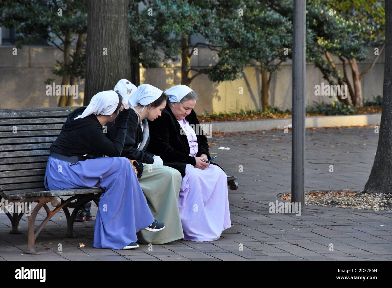 Washington DC. November 14, 2020. Million Maga March. Three Amish women sitting on the bench looking at the phone. Stock Photo