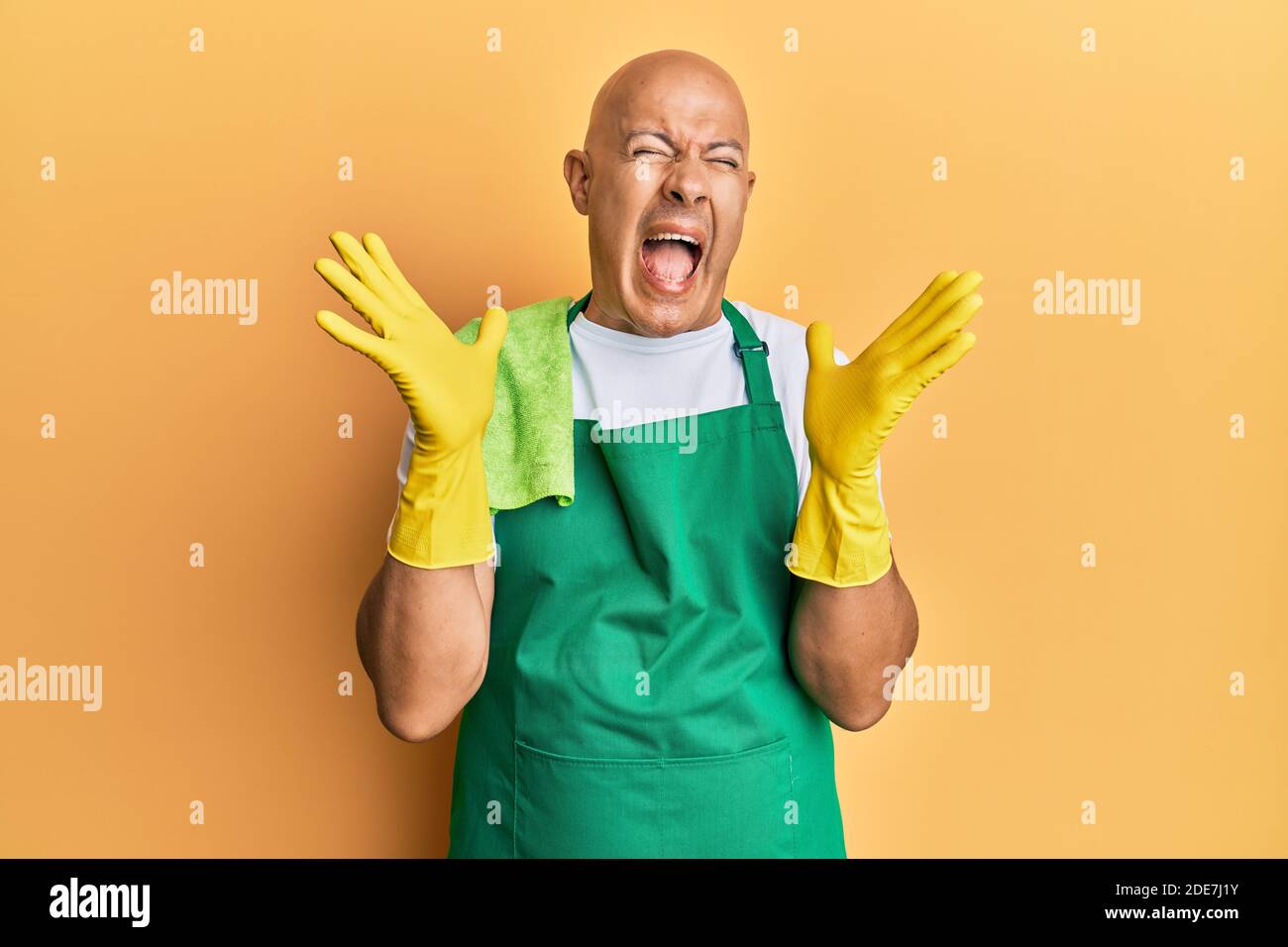 Middle Age Bald Man Wearing Apron Holding Cleaning Gloves Celebrating