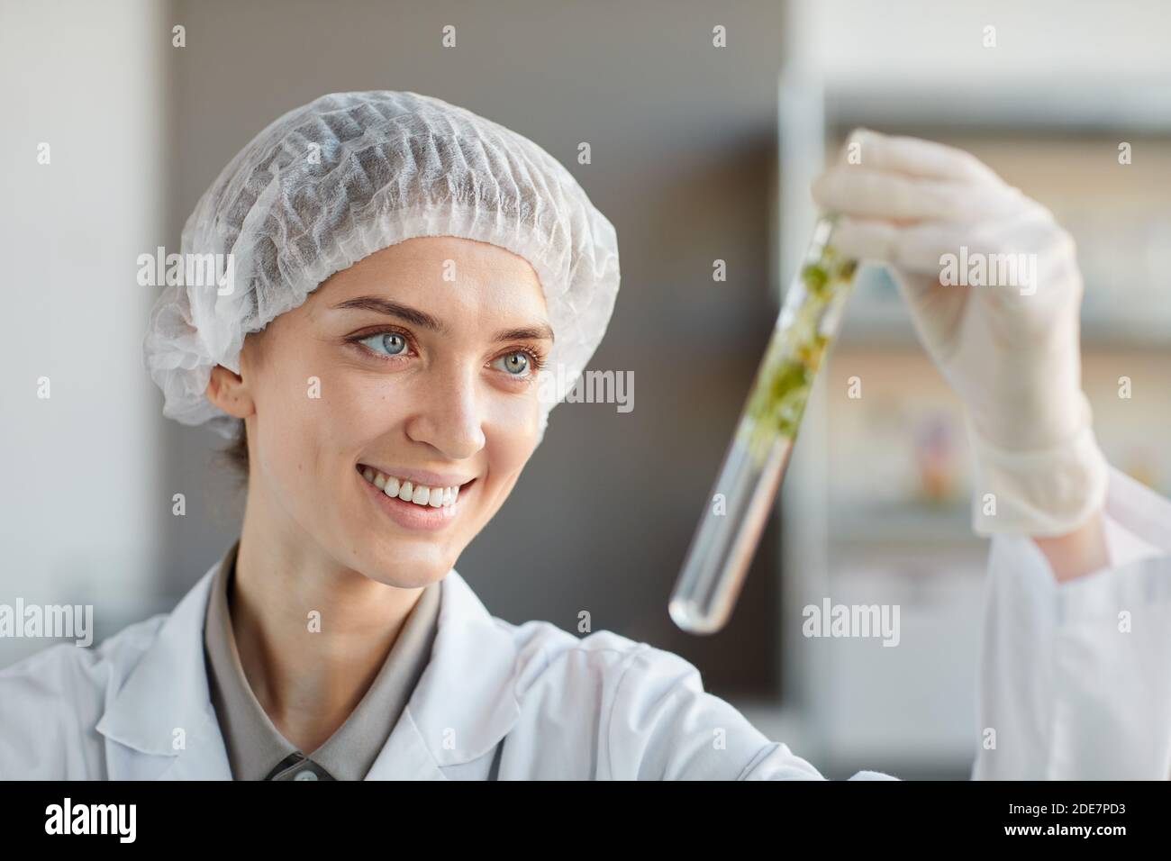 Close up portrait of smiling female scientist holding test tube with plant samples while working on research in biotechnology lab, copy space Stock Photo