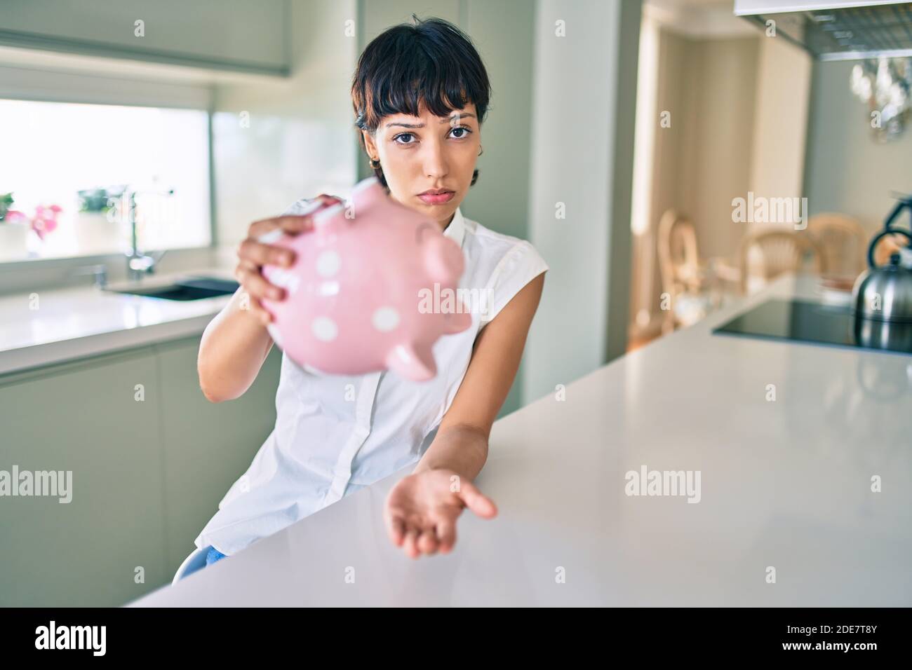 Young brunette woman showing empty piggy bank with sad face Stock Photo