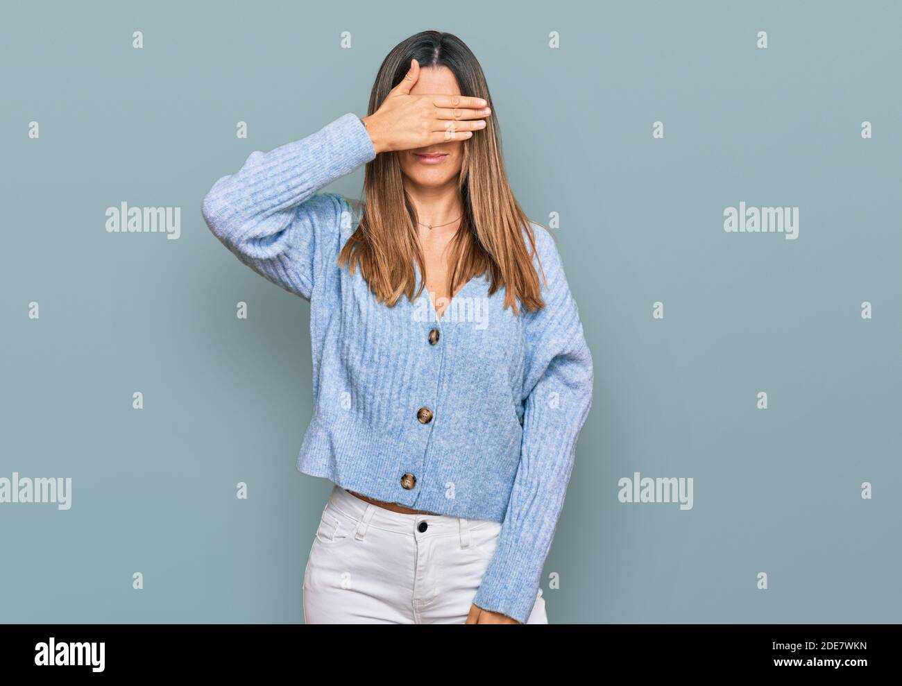 Young woman wearing casual clothes covering eyes with hand, looking serious and sad. sightless, hiding and rejection concept Stock Photo