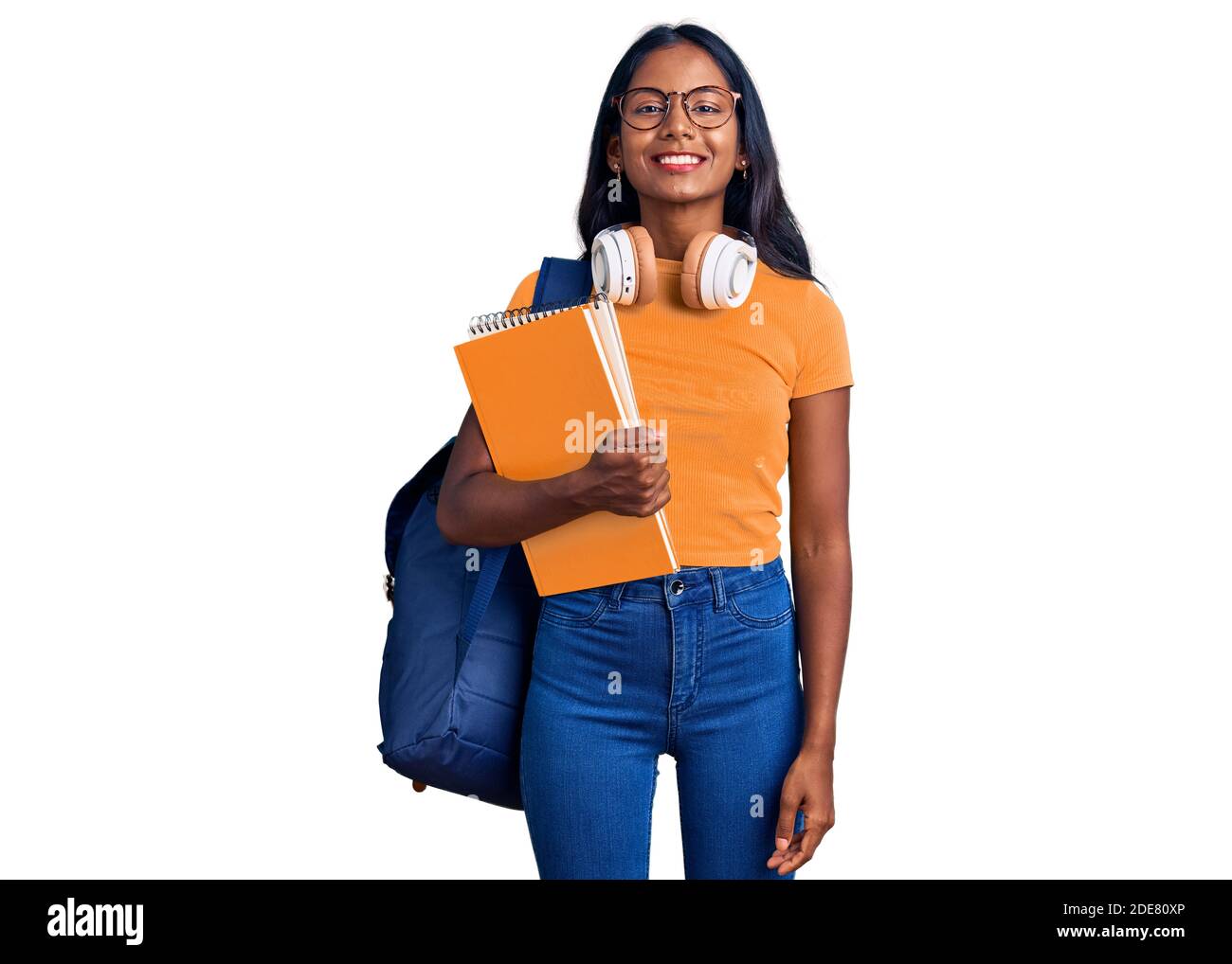 Young indian girl holding student backpack and books looking positive ...