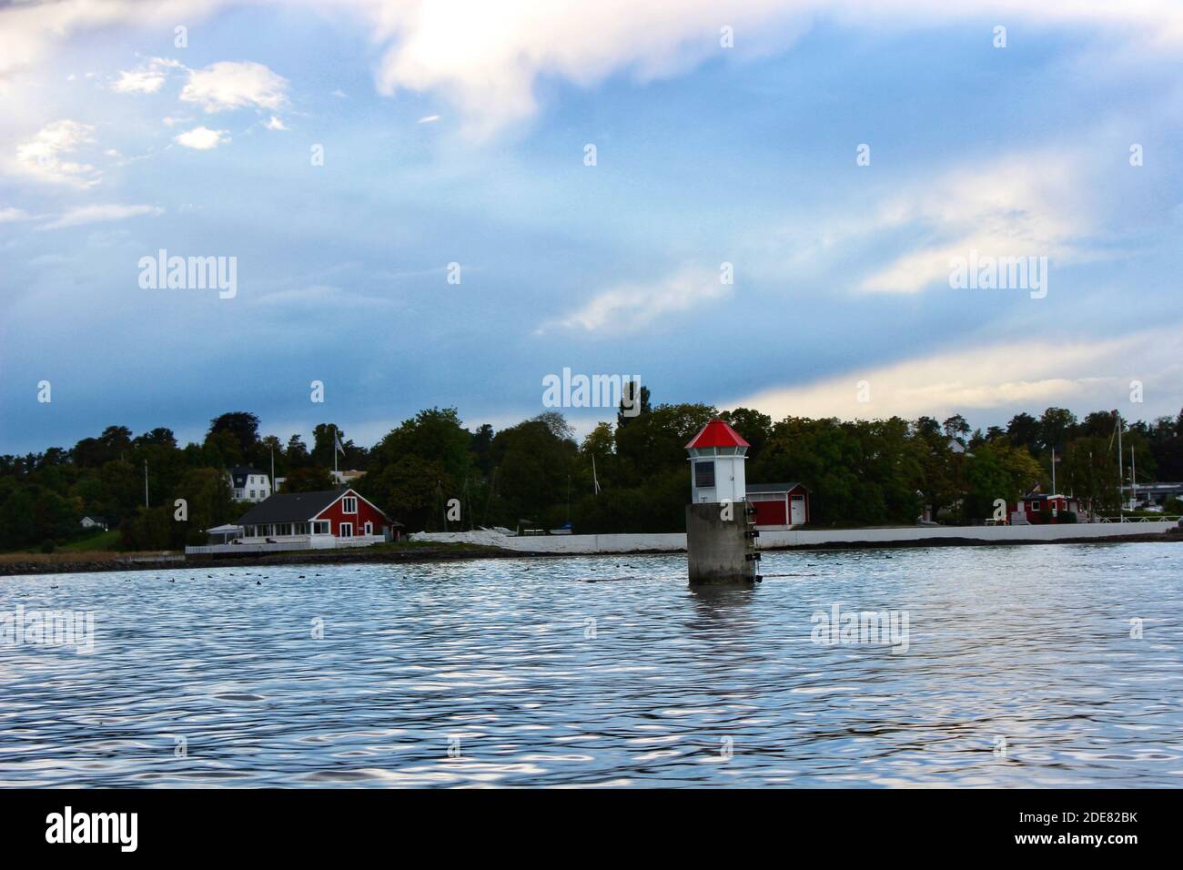 Concrete pole with little house with red roof atop in sea water just off a Fjord outside of Oslo Stock Photo