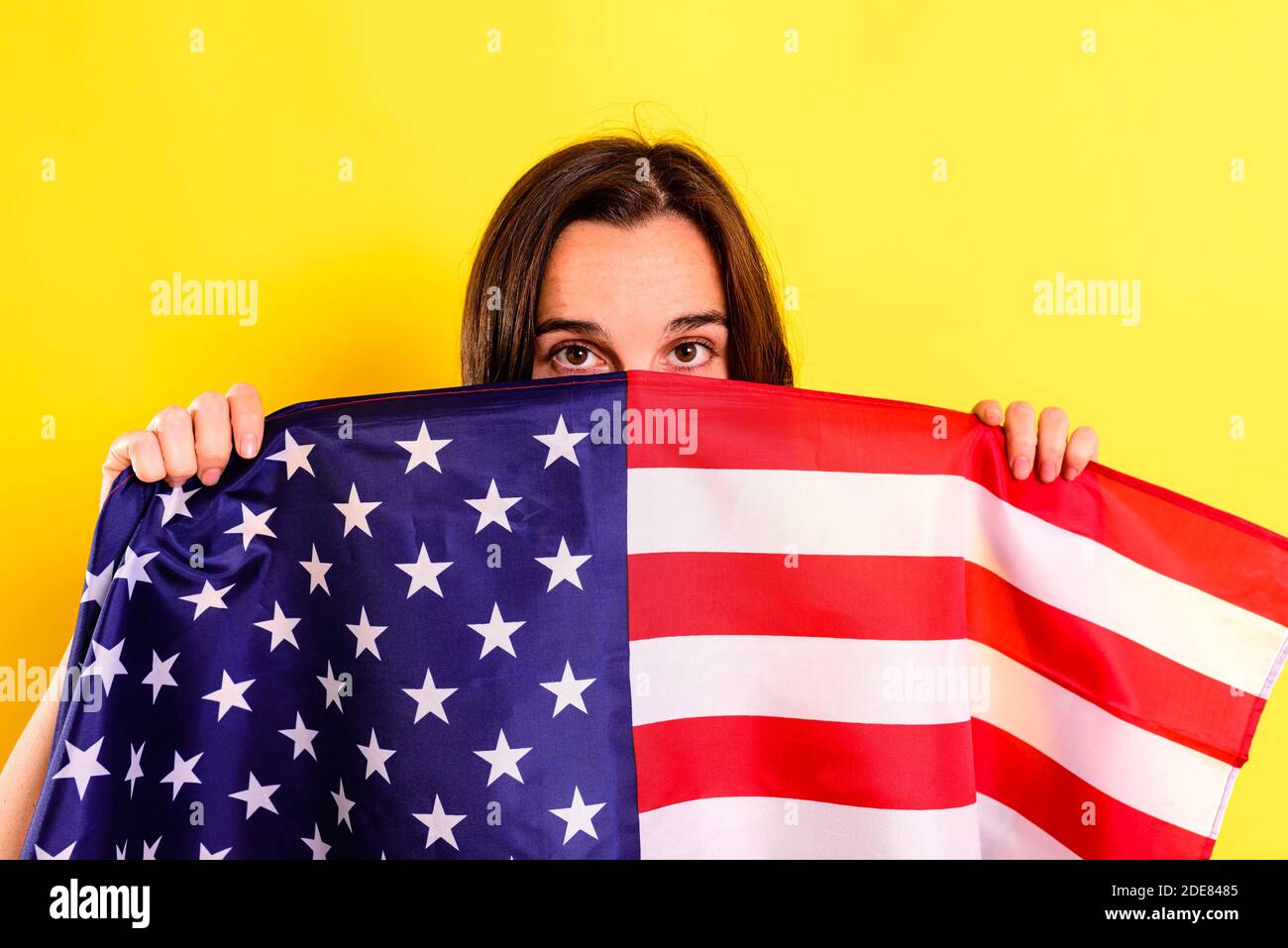Young embarrassed woman covers herself with an American flag to