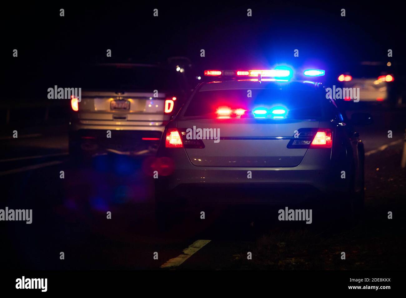 Police emergency flash lights at night from the back on highway road Stock Photo