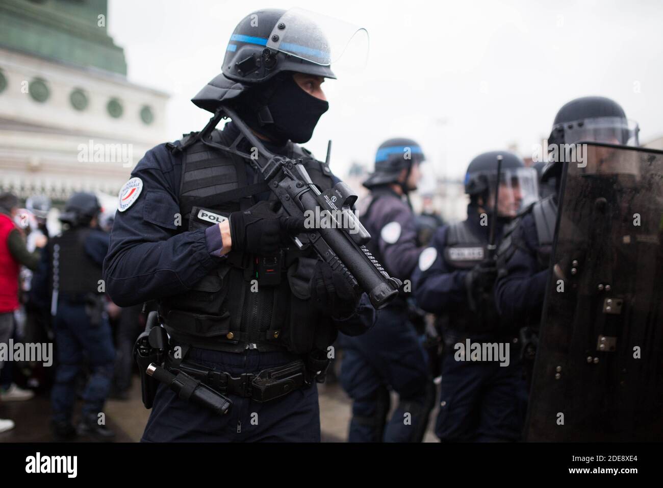 A riot police officers aims at protesters his rubber bullets gun flash ball  lbd 40 during clashes with on the sideline of an anti-government  demonstration called by the Yellow Vests "Gilets Jaunes"