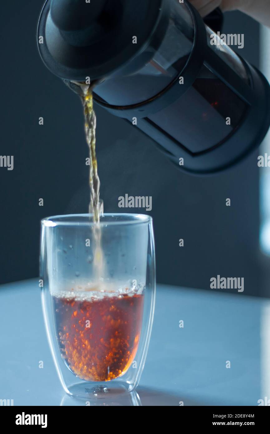 french press black tea pouring into a glass with a double bottom on a