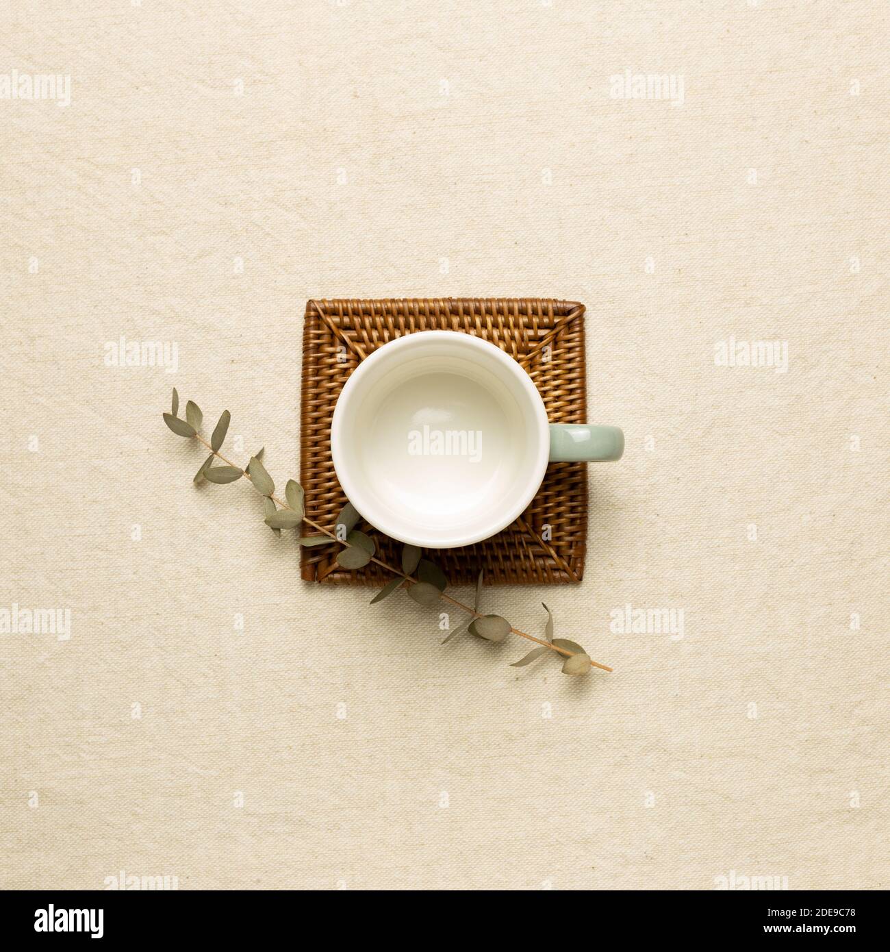Empty mug cup with eucalyptus leaf on beige fabric background. top view Stock Photo