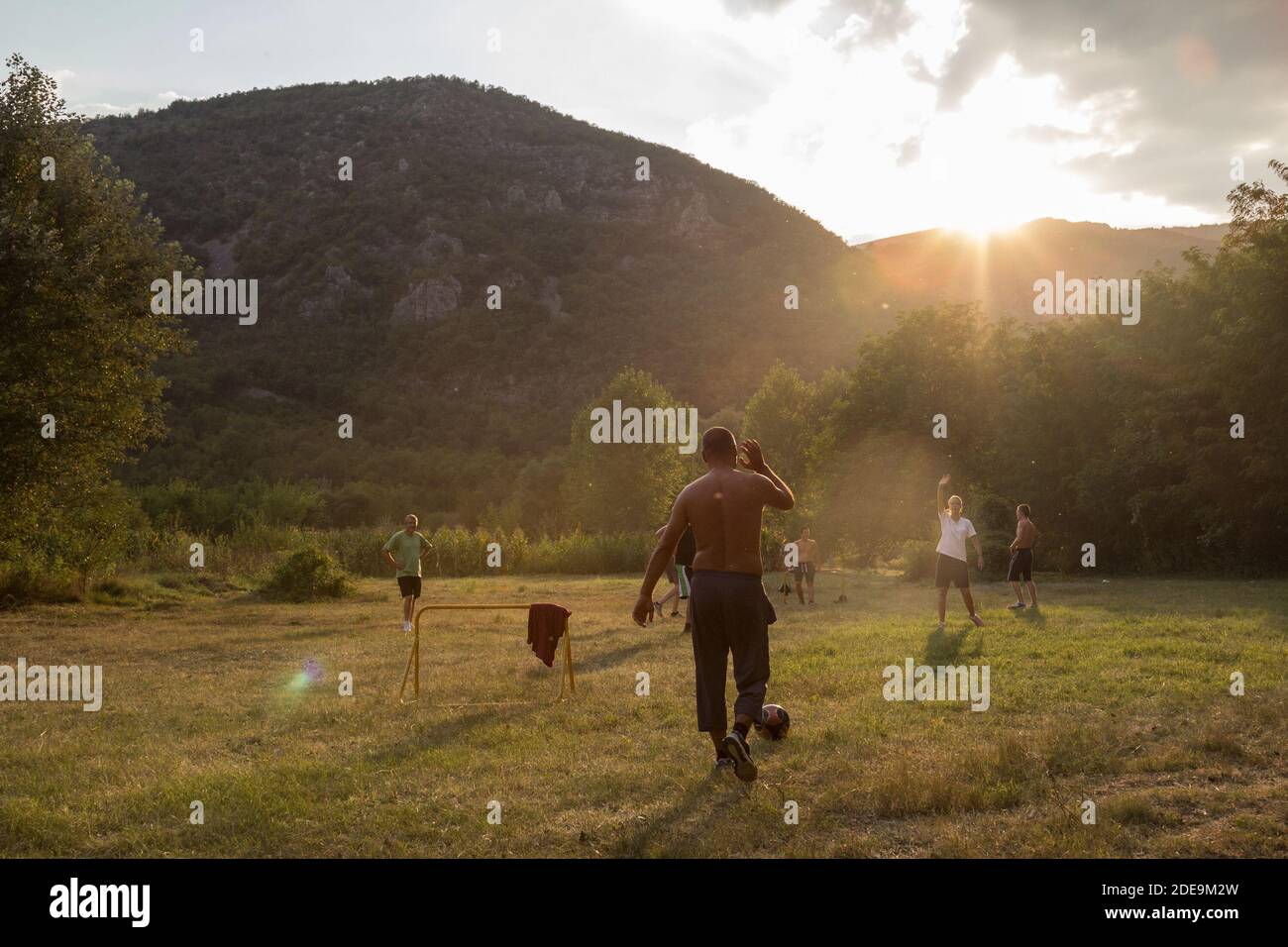 SUVA PLANINA, SERBIA - SEPTEMBER 3, 2016: People, mostly men, playing soccer football in a countryside field at dusk in Suva planina, one of the main Stock Photo