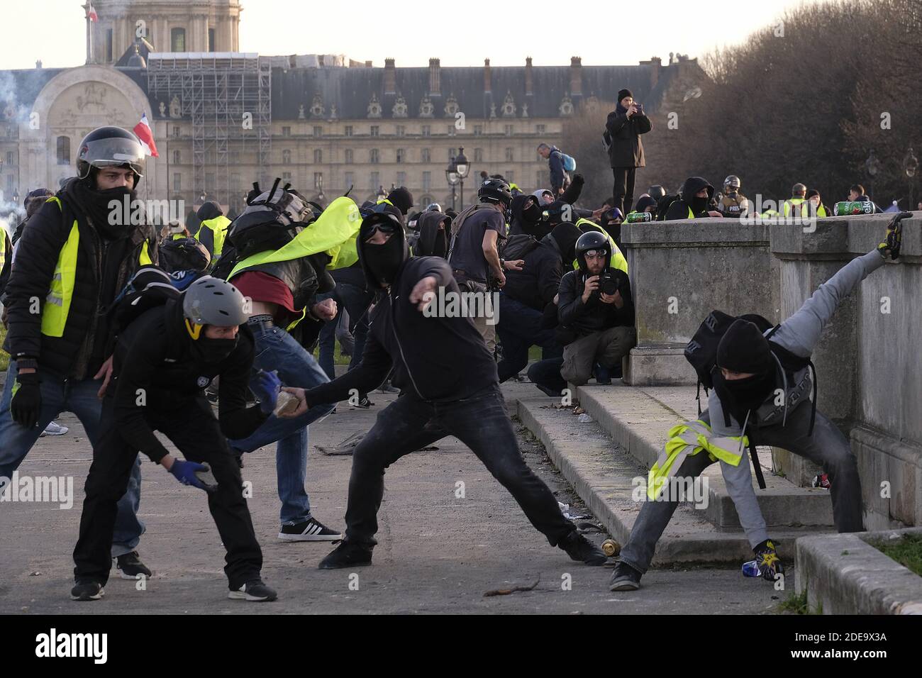French yellow vests (Gilets jaunes) protesters throw stones during clashes  with French riot police on the Esplanade des Invalides during the 14th  consecutive week of nationwide Yellow Vest (Gilets Jaunes) movement protests