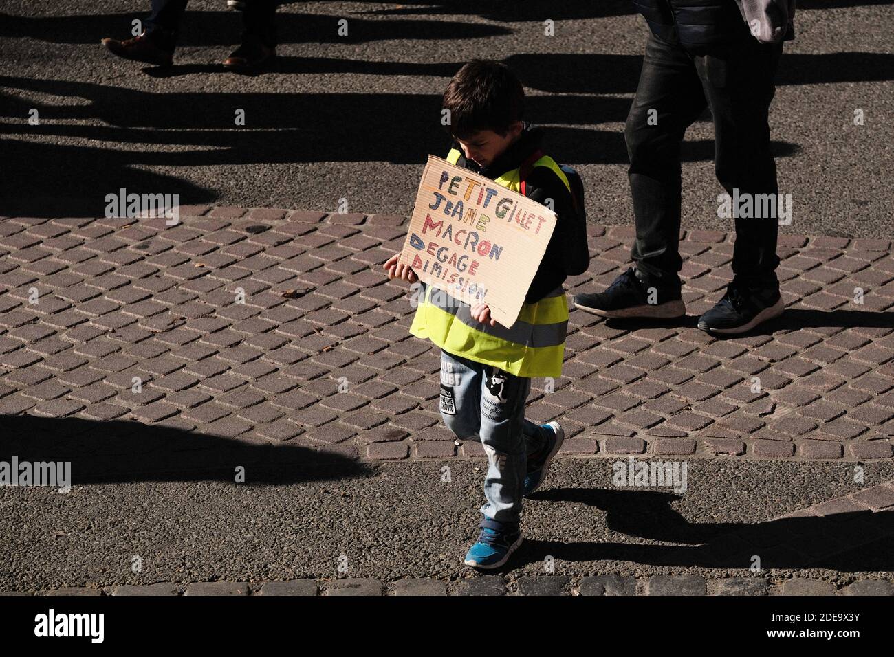 Young boy with sign "Petit gilet jaune : Macron dégage, démission" (Small  yellow jacket : Macron, clear, resign). Several thousand protesters in the  streets of Toulouse (France) for the 14th Saturday of