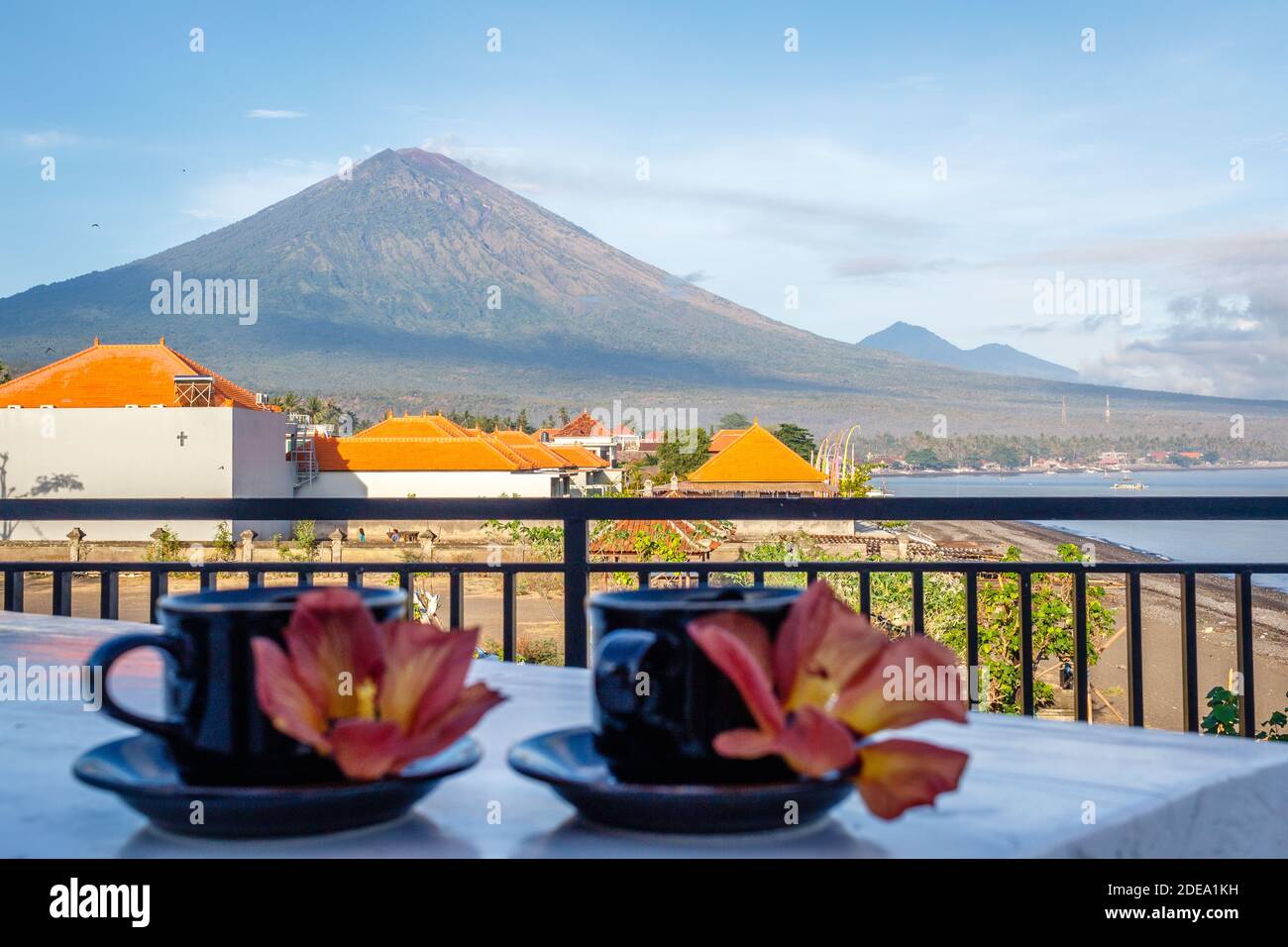 Two cups of coffee with flowers of Hibiscus Tiliaceus or Sea hibiscus, view of volcano Agung on the background. Amed, Karangasem, Bali, Indonesia. Stock Photo