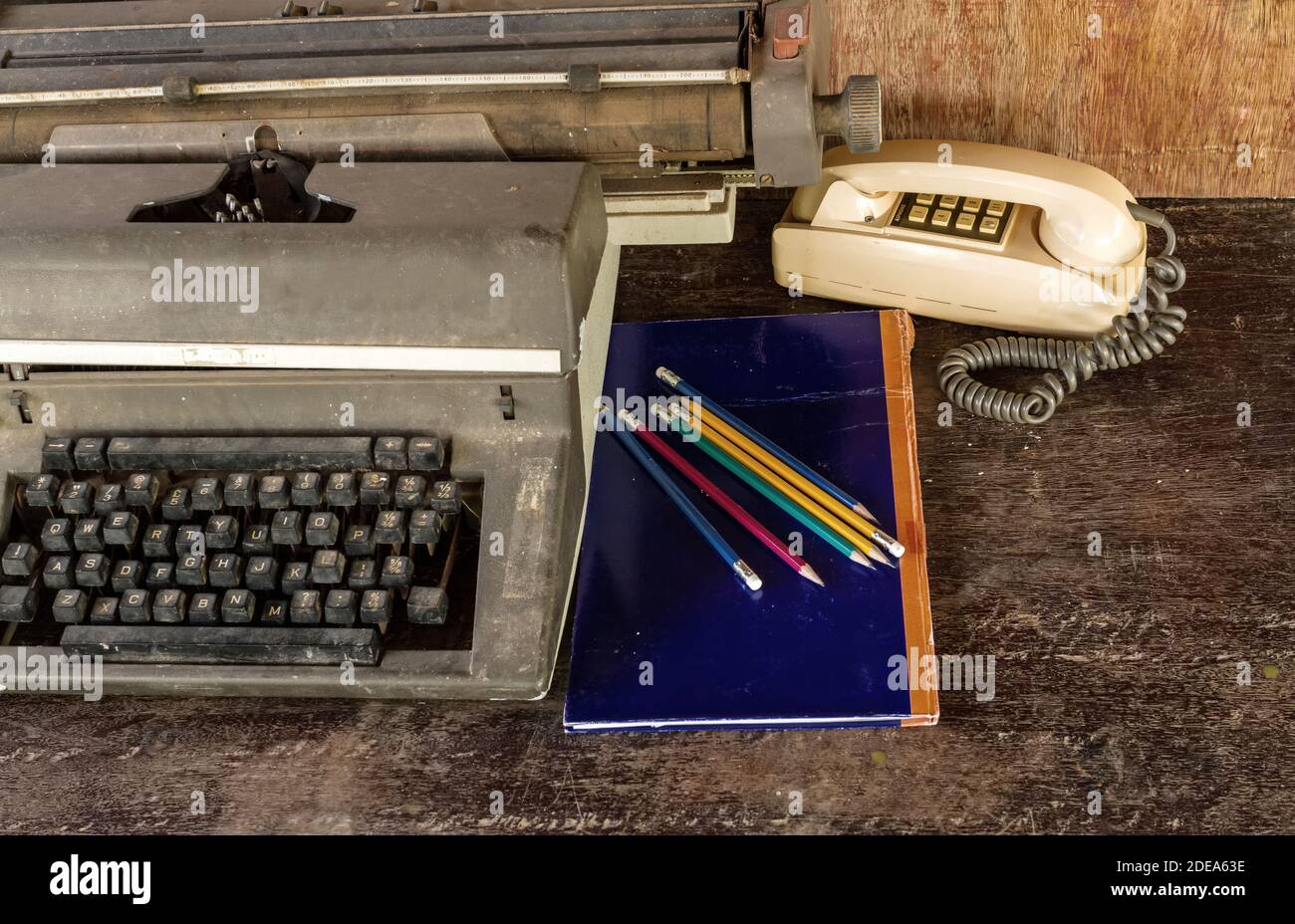 Vintage typewriter ,blue  book,  ,pencil and old telephone on old wooden touch-up in still life concept Stock Photo