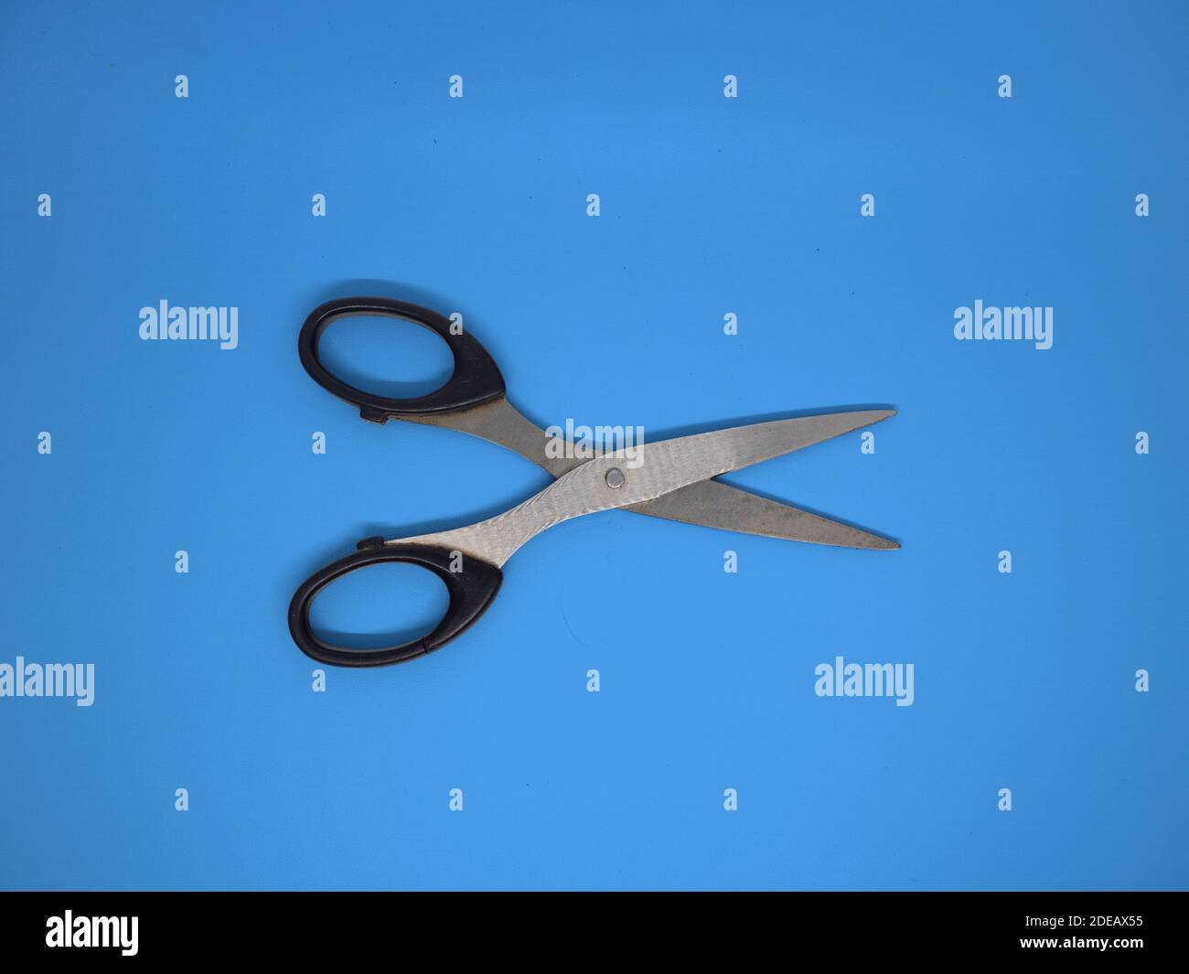 An open scissor with isolated blue background Stock Photo