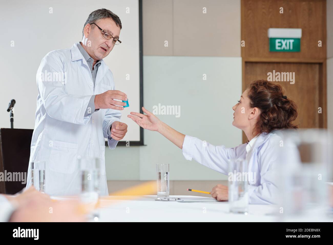 Scientist giving vaccine to colleague Stock Photo