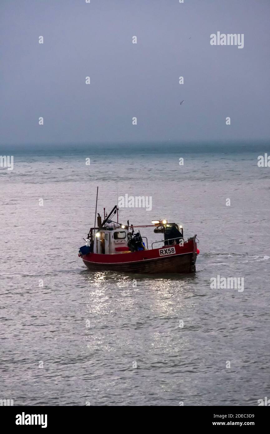 Hastings fishing boat setting out to sea at dawn to fish in the English Channel, East Sussex, UK Stock Photo