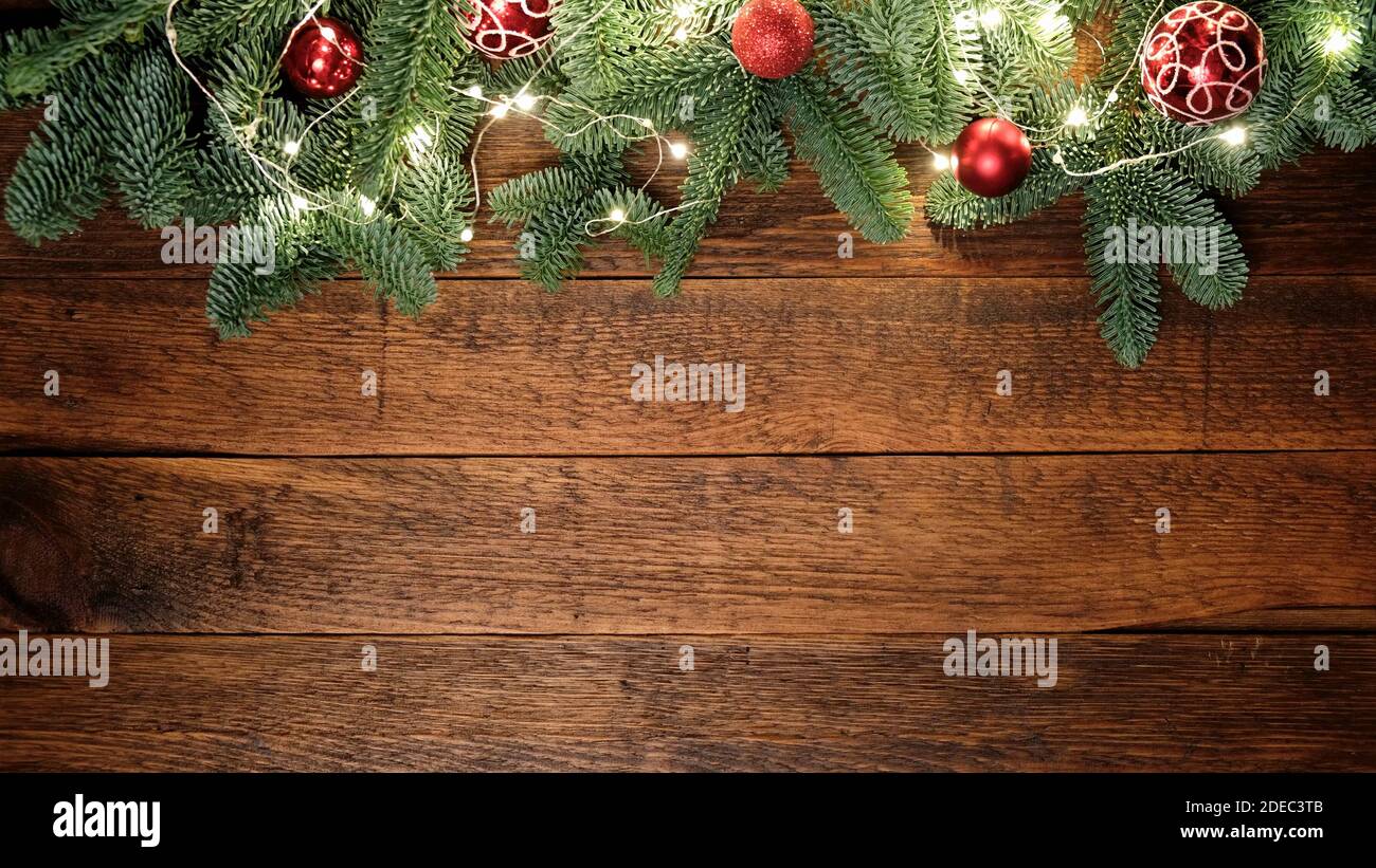 Christmas, New Year background composition with copy space. Fir tree with decorations and Christmas lights on rustic wooden background. Top view Stock Photo