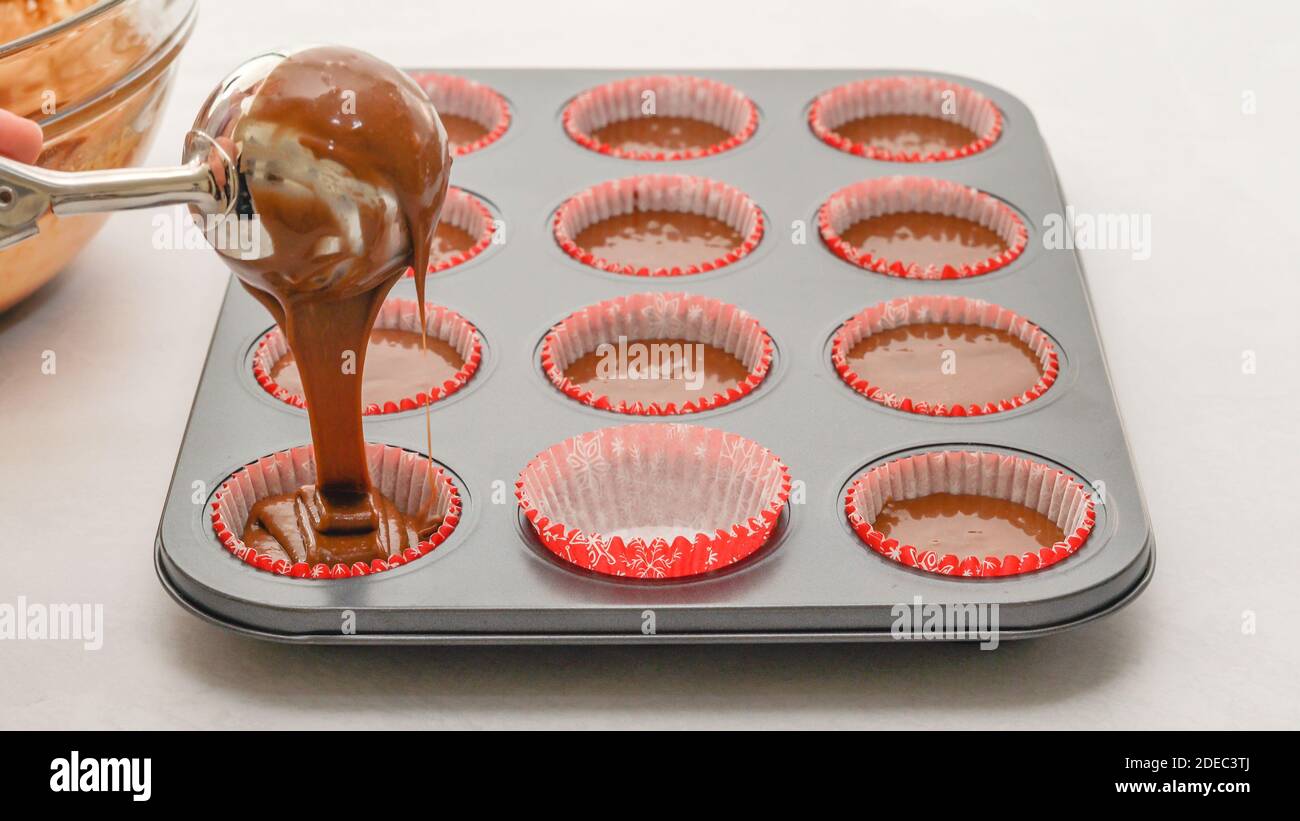 Chef pouring chocolate cake batter into a lined cupcake pan. Chocolate