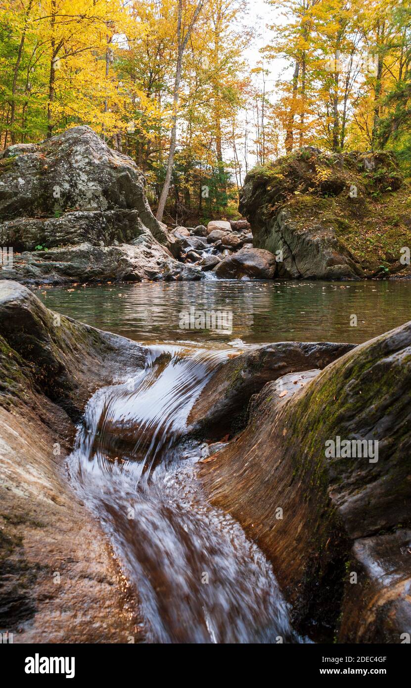 Stream cascading down between large boulders into a crystal emerald