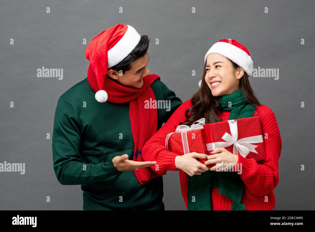 Happy Asian woman being surprised with Christmas gift boxes by her boyfriend Stock Photo