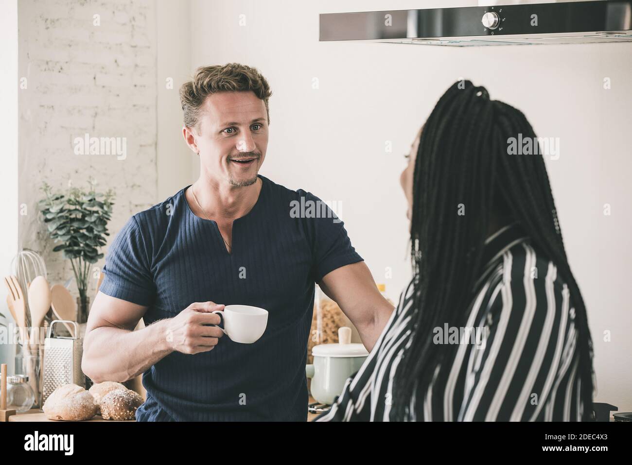 Happy interracial couple talking together having a good time at home in the morning Stock Photo