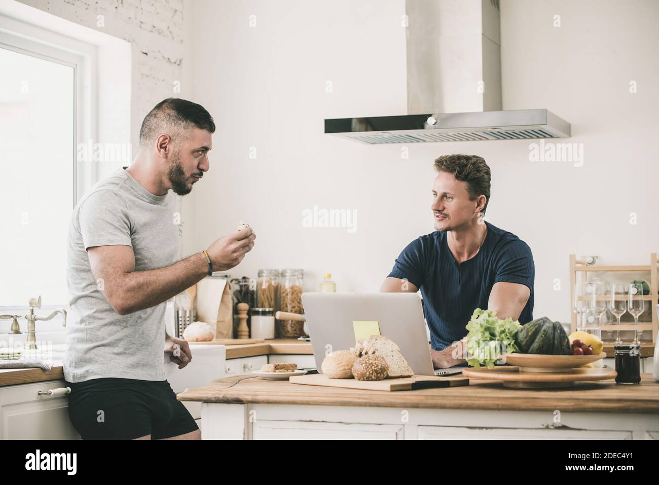 Gay male couple seriously talking at home while doing morning routines, LGBT lifestyle concept Stock Photo