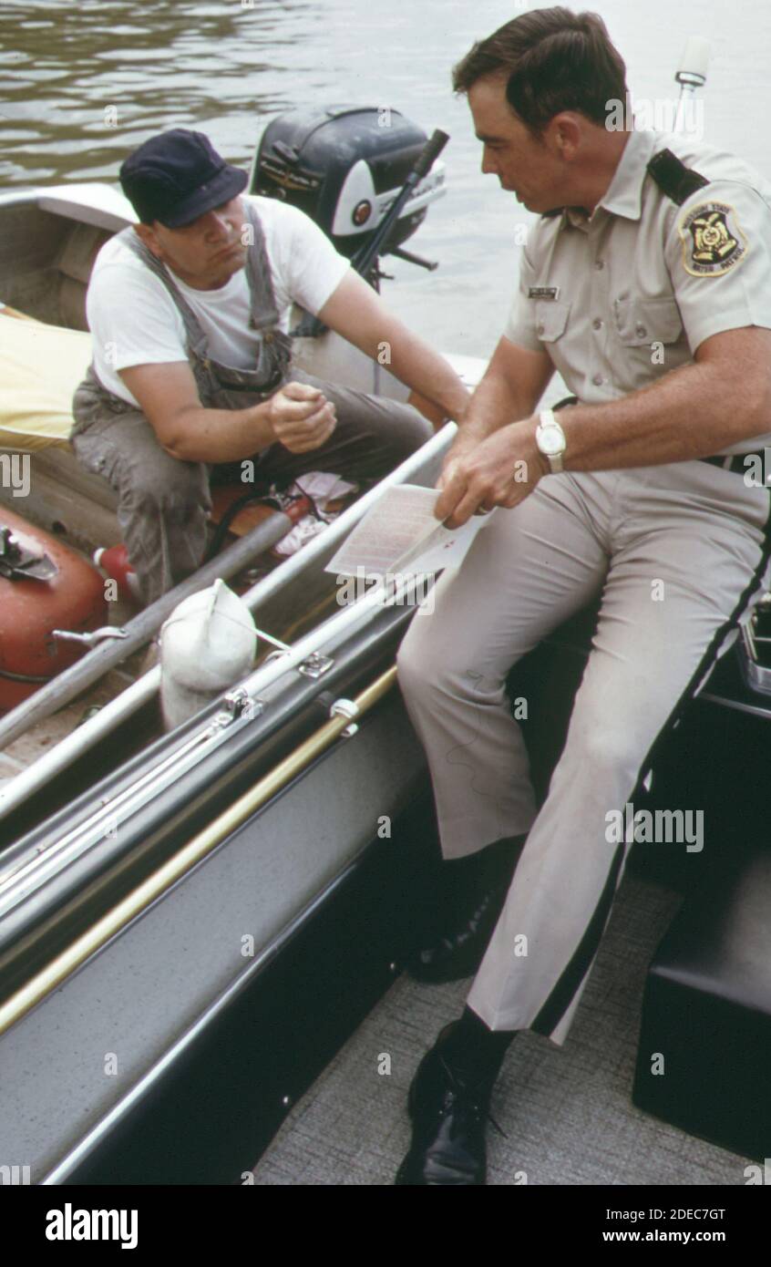 1970s Photos (1973) -  Water patrol supervisor dan needham issues a warning to fisherman for failure to display appropriate licensing on the bow of his boat. encounters between the water patrol and the public appear to be handled both cordially and professionally  (Lake of the Ozarks Missouri area) Stock Photo