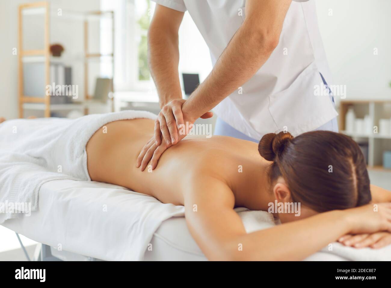 Lying woman patient getting massage of back from professional chiropractor or masseur Stock Photo