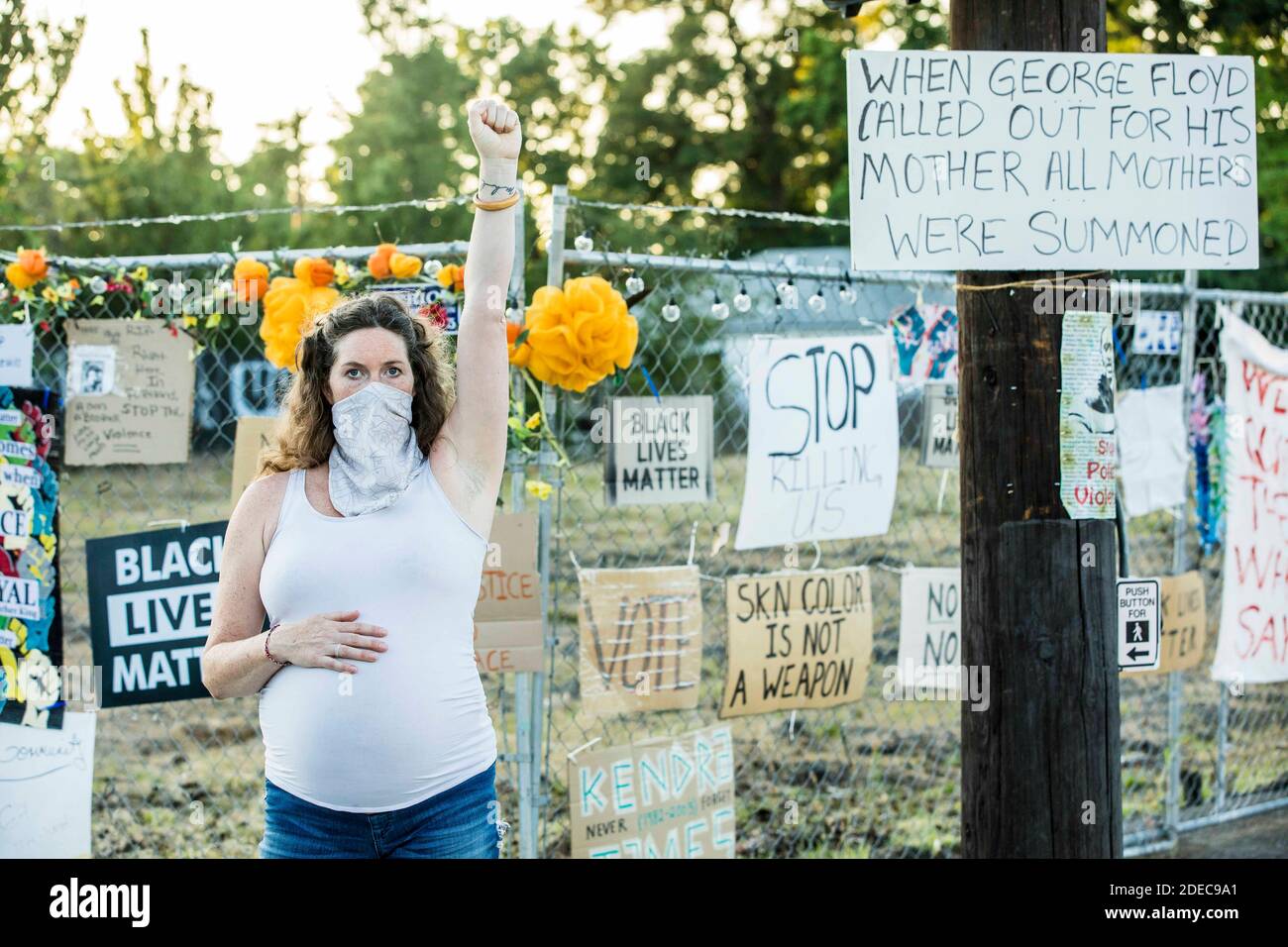 Portland, Oregon, USA. 25th Aug, 2020. HEATHER HAWKSFORD, fist held high and wearing a white mask and on her other hand resting on very pregnant belly, mother to 3 children and 9-months pregnant, documentary filmmaker, photographer, wife. Heather was one of the first 30 women (in what later became known as The Wall of Moms) who marched to the Justice Center chanting, ''Have no Fear. Moms are Hear.'' Heather and her son, work together to prepare dinner at their home. ''White accountability starts at home, so I am mostly working hard to raise my kids to be aware, anti-racist, compassionate and Stock Photo