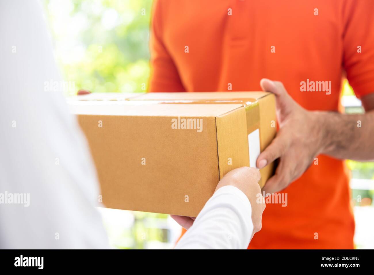Courier service delivery man in orange uniform giving parcel box to