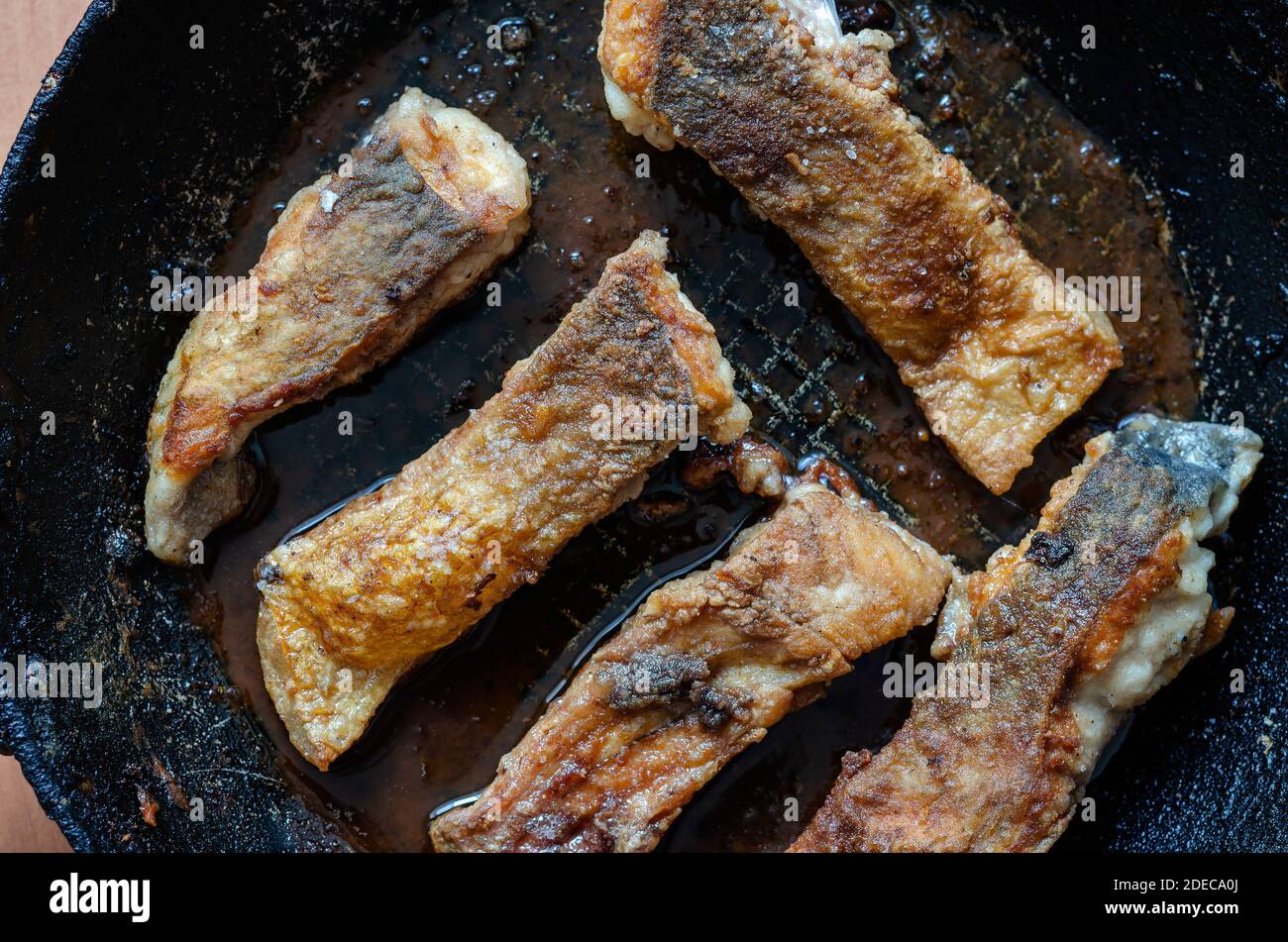 Portions of fish fried to golden crust in frying pan. Fried fish with ...