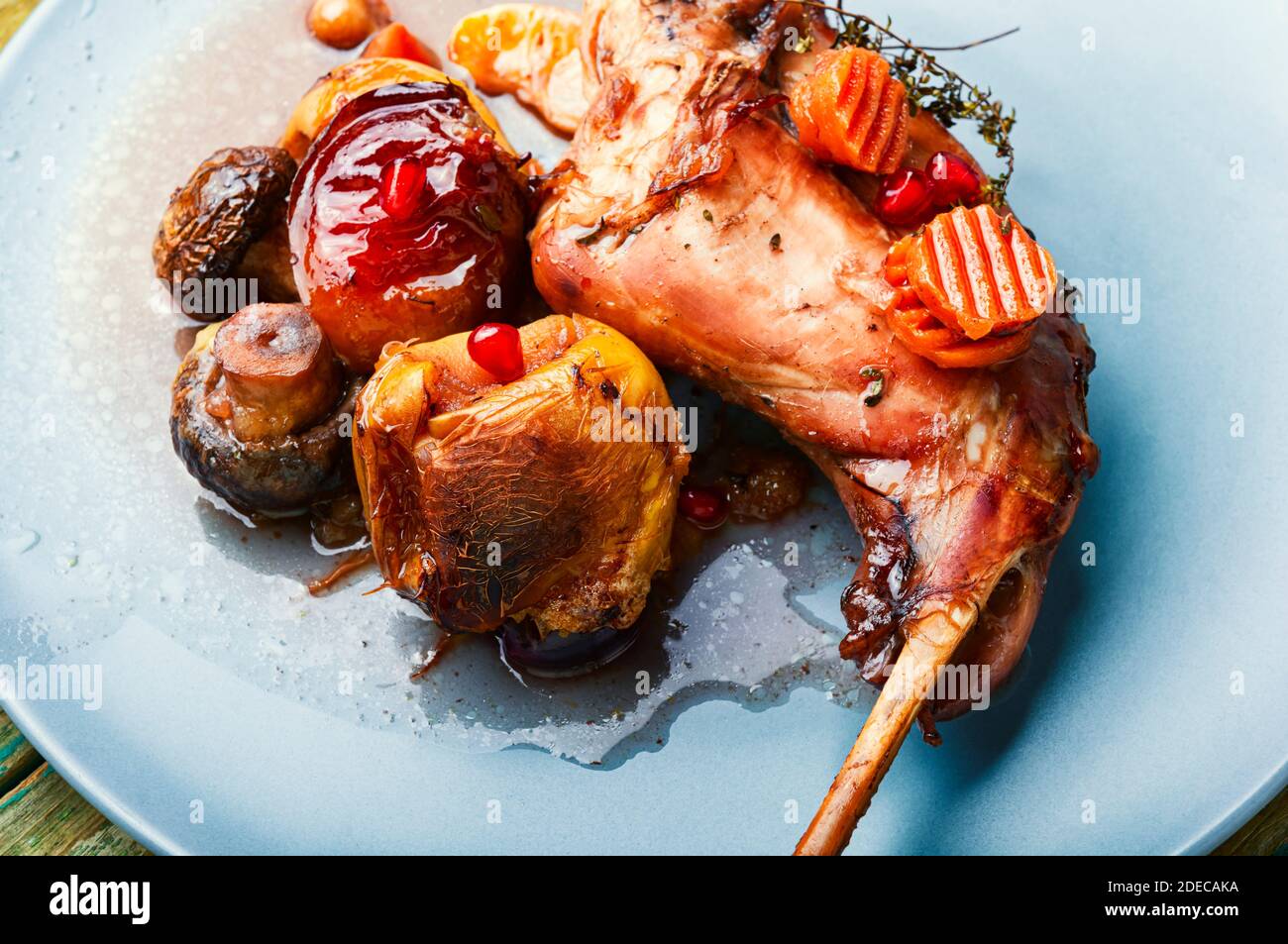 Baked rabbit leg with apples, carrots and mushrooms. Stock Photo