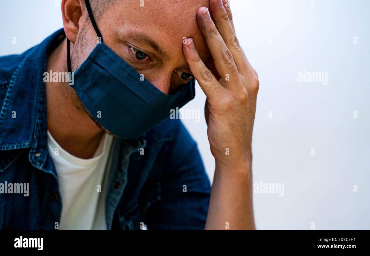 Man wearing a protective face mask starring into nothing looking depressed. . High quality photo Stock Photo
