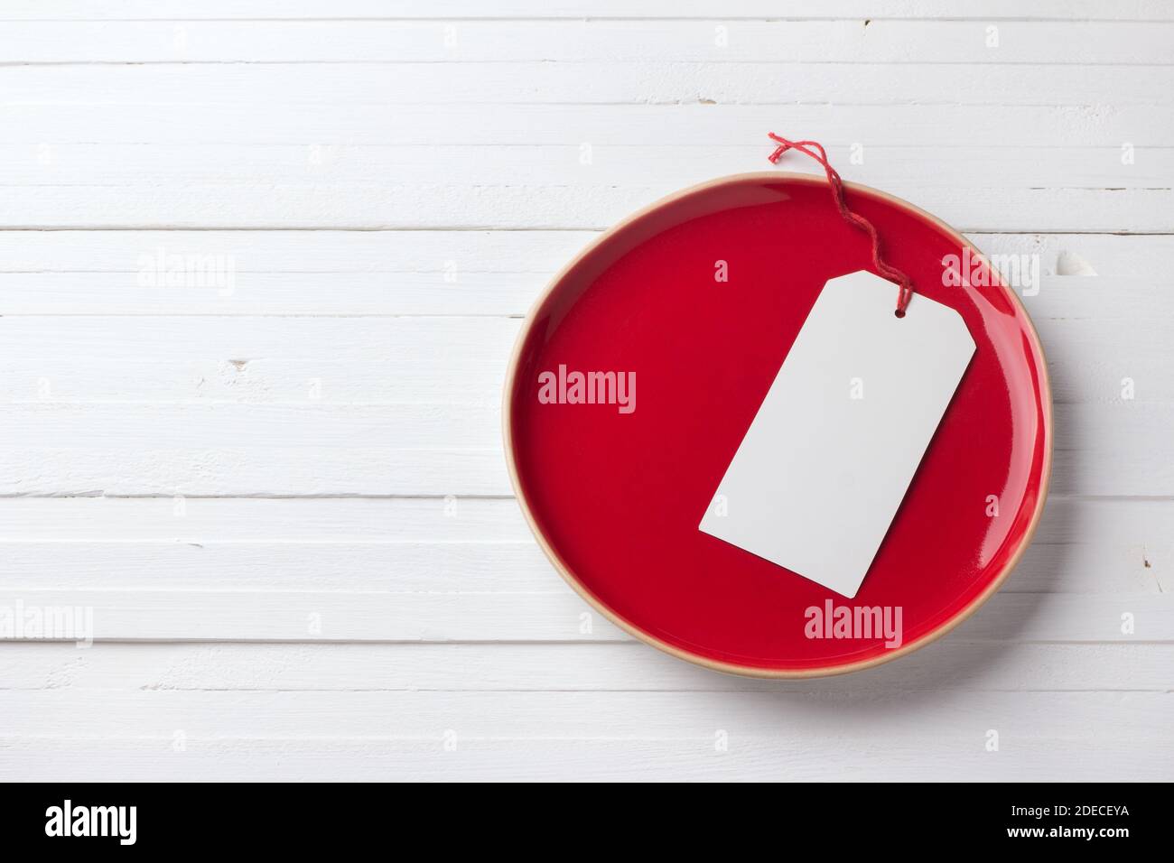 Red vintage plate with a white blank tag on a white background Stock Photo