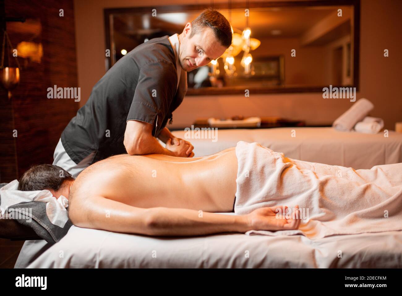 Professional masseur doing a spine massage on a male client applying  pressure along the vertebrae with his forearm in a close up cropped view  Stock Photo - Alamy