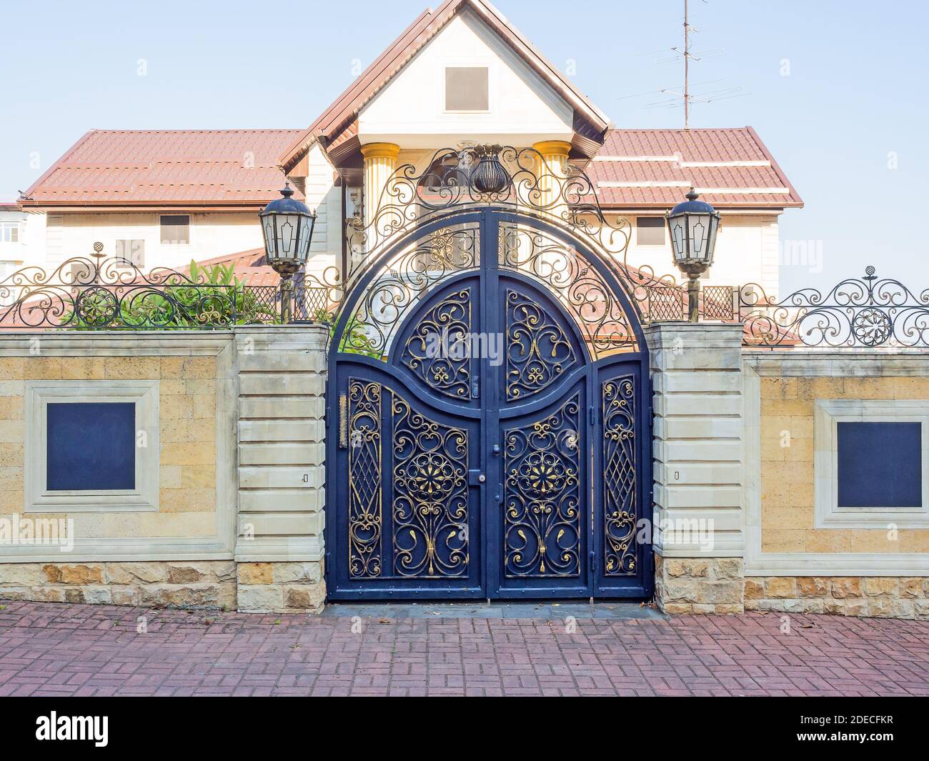 Private villa with stone fence and iron decorative gates with a wrought