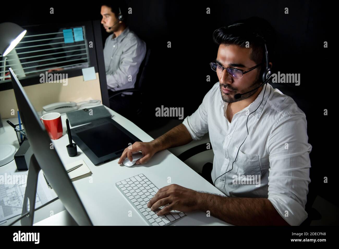 Asian technical support team working night shift in call center office talking with customers in different time zone Stock Photo