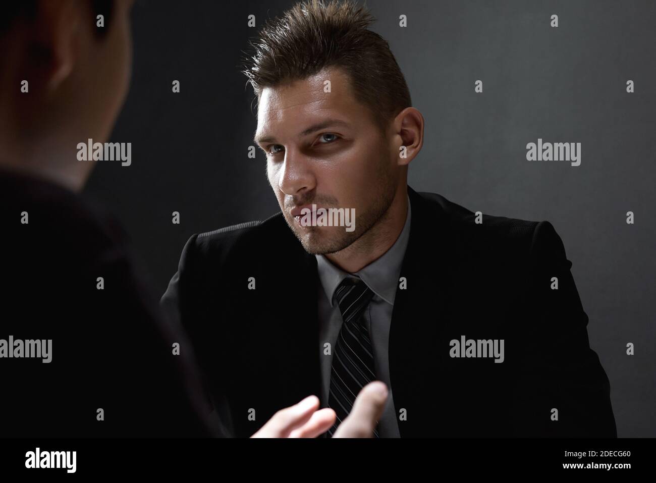 Detective interviewing suspect or criminal man in dark interrogation room Stock Photo